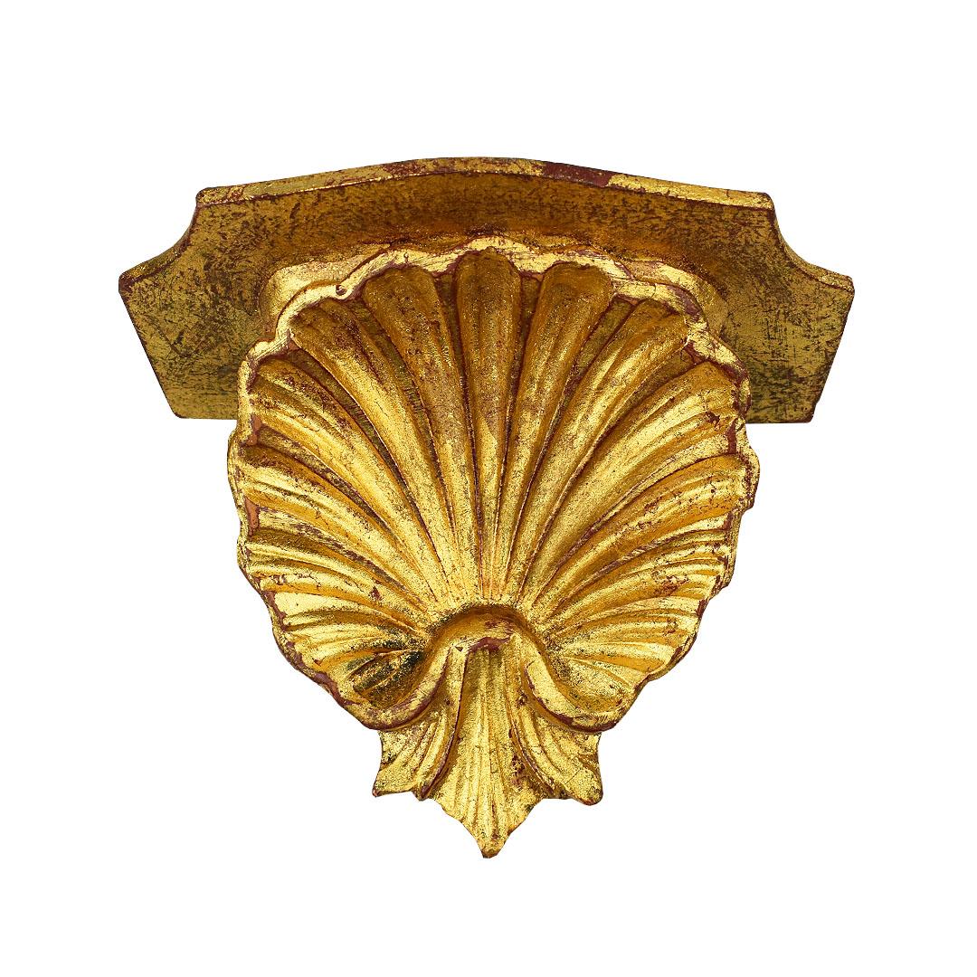 Small grotto-style bracket shell shelf in gold. The top of this piece has a small scalloped top and a large shell at the bottom. The back features two metal hanging pieces for easy installation. Made in Italy and created from wood. 

How We Would