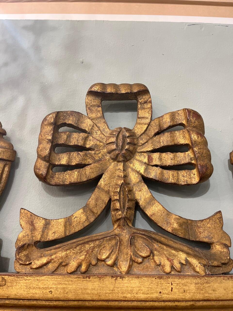 Italienischer Spiegel aus Giltwood im neoklassischen Stil des 20. Jahrhunderts, mit verschnörkeltem unteren Rand und einem durchbrochenen Bogenknoten, der von kannelierten Urnen flankiert wird