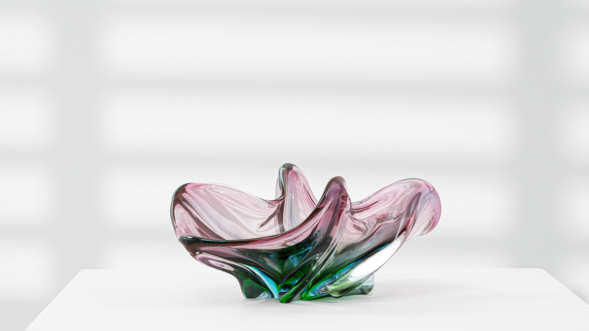 This 20th Century Italian glass plateau showcases the vibrant artistry of mid-century Murano design. Rendered in a striking blend of pink, green, and clear glass, the piece embodies fluidity and motion through its organic, free-form silhouette. Each