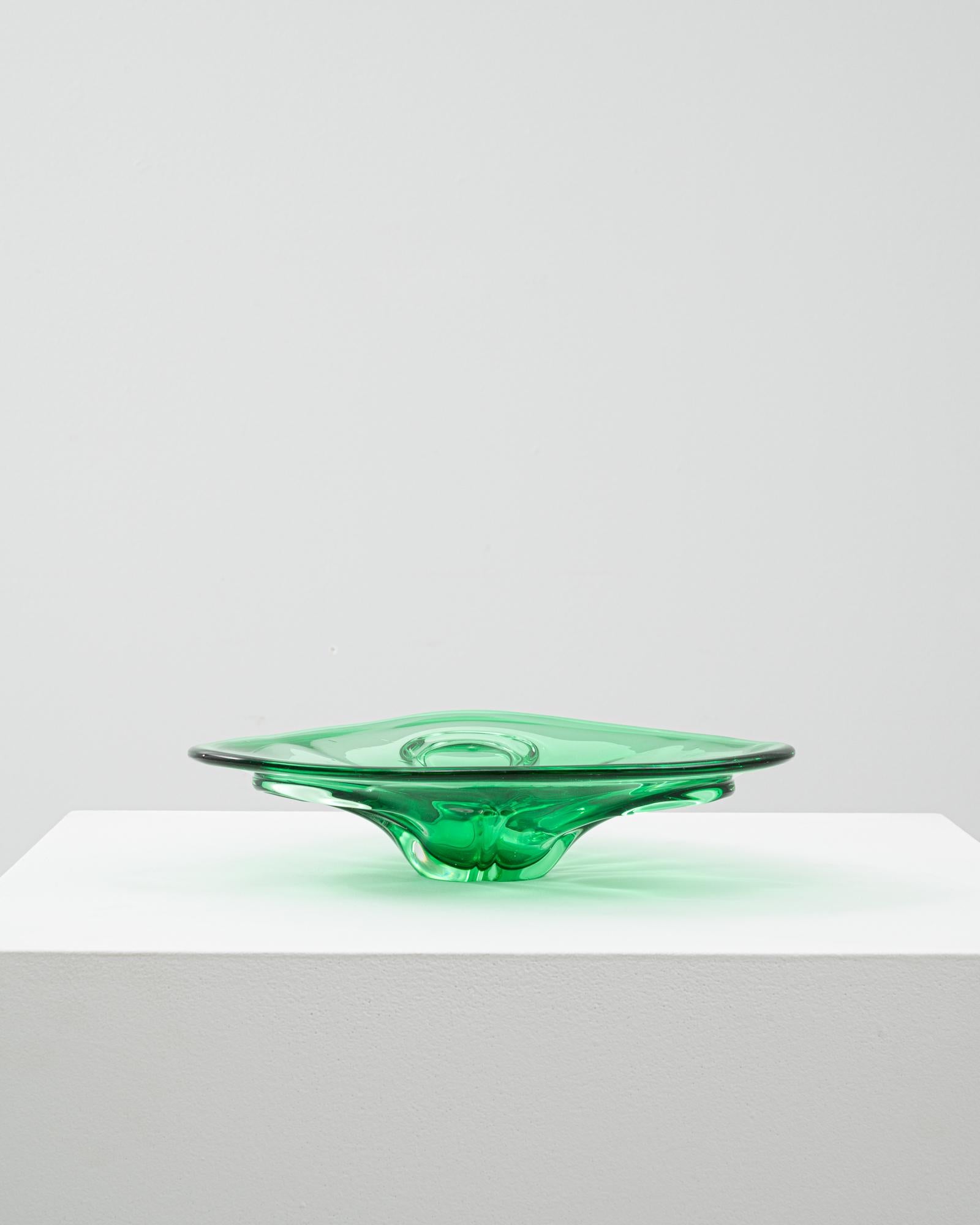 This 20th Century Italian glass plateau features a sleek, low-profile design with a sculptural base, rendered in vibrant emerald green. Its smooth, fluid surface showcases the precision and artistry of Murano glassmaking, capturing and refracting