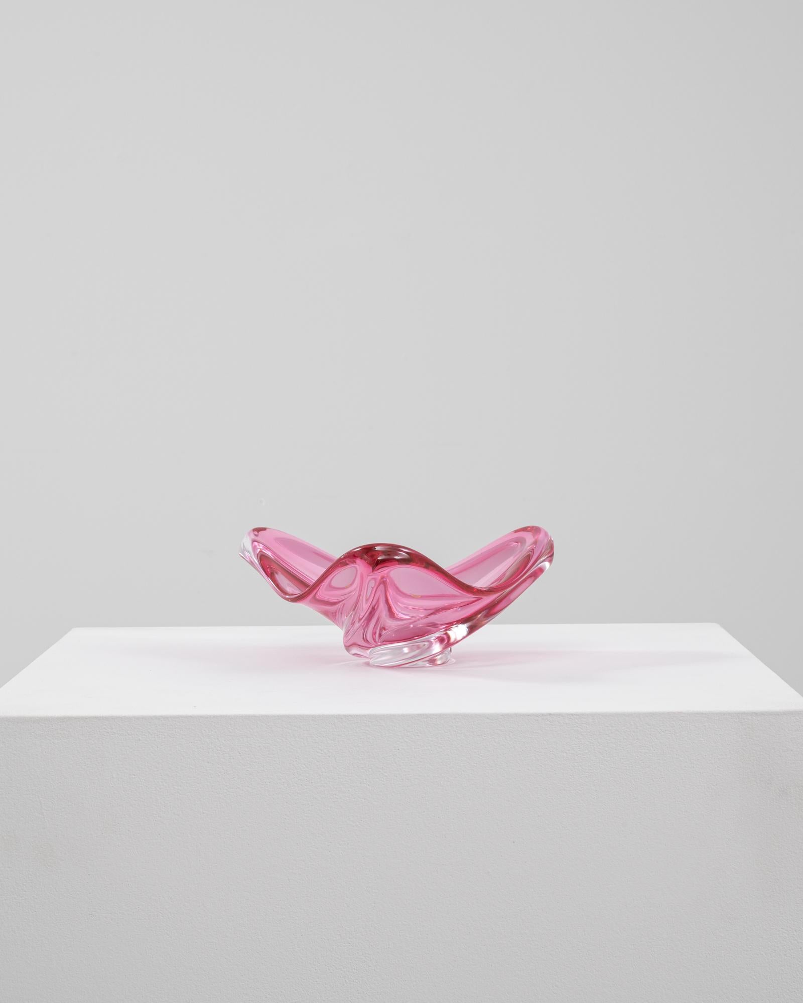 This 20th Century Italian glass plateau is a vibrant expression of mid-century artistry, rendered in a rich pink hue with a clear base. The compact form features elegantly arched sides that curl outward in a fluid, sculptural motion, showcasing the