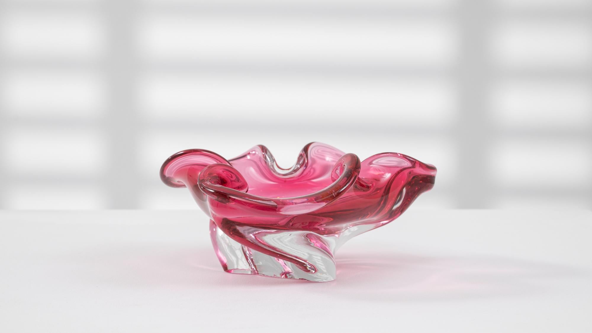 This 20th Century Italian glass plateau is a playful yet elegant example of Murano-style craftsmanship. Featuring a vivid pink coloration that blends into a clear glass base, the piece is defined by its undulating, ruffled rim and sculptural swirls.