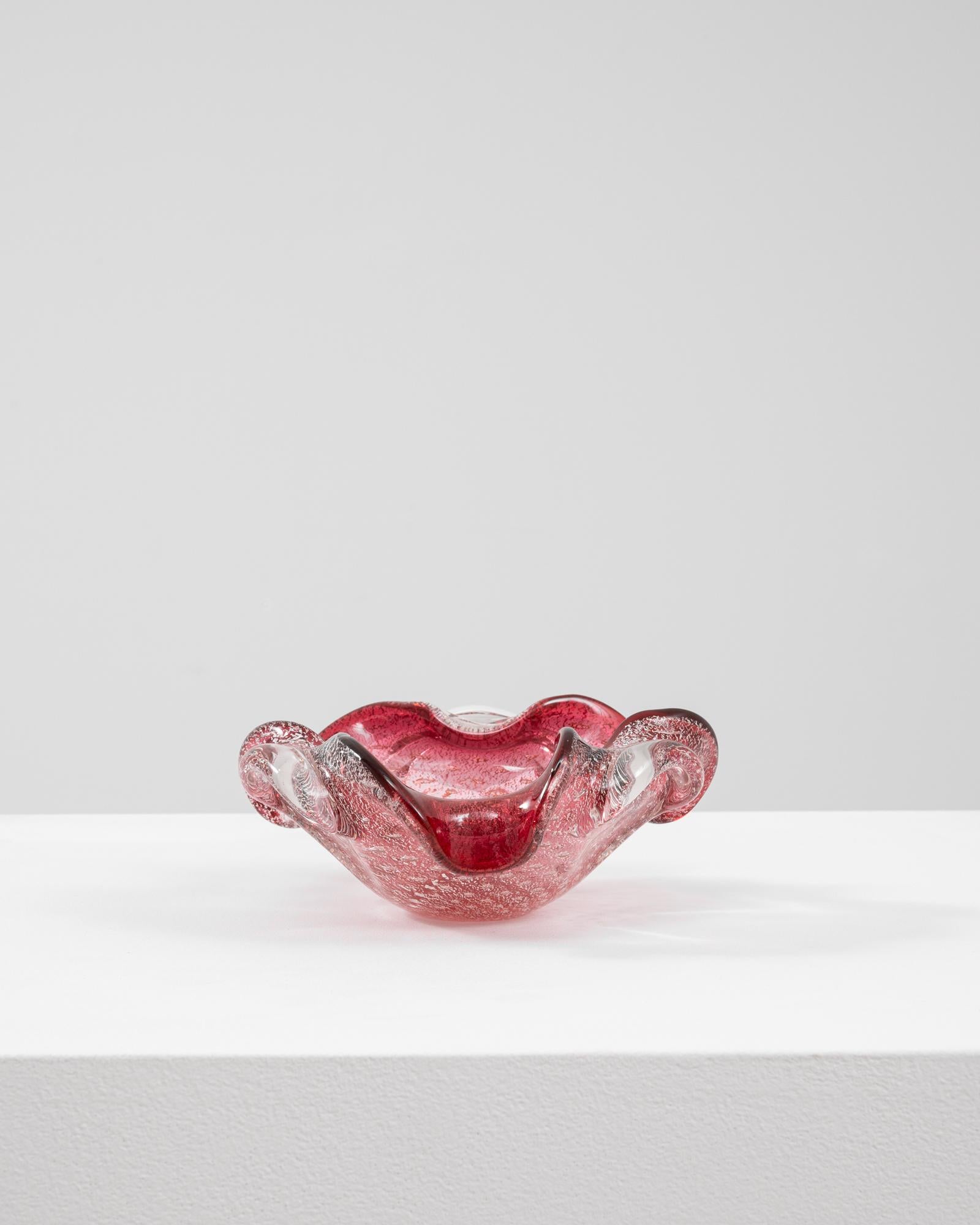 This 20th Century Italian glass plateau is a refined example of Murano artistry, distinguished by its controlled bubble inclusions and rich ruby red tone. The bowl-like form features curled edges and a textured surface that gives it a tactile,