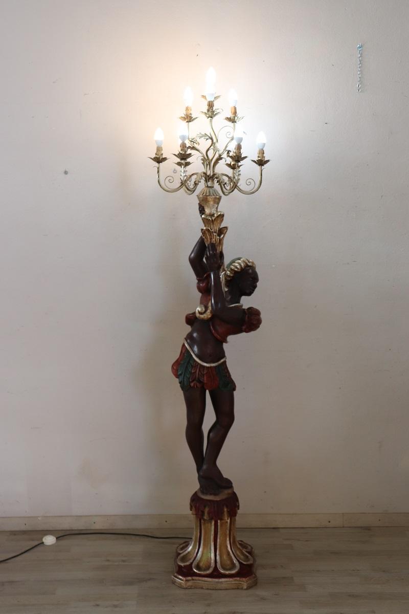 A true sculptural work of art this beautiful floor lamp. A typical Venetian Moor made of hand-carved and hand-painted wood on a plaster base. The Moor holds a cornucopia that ends with a golden metal structure equipped with 10 light bulbs. This