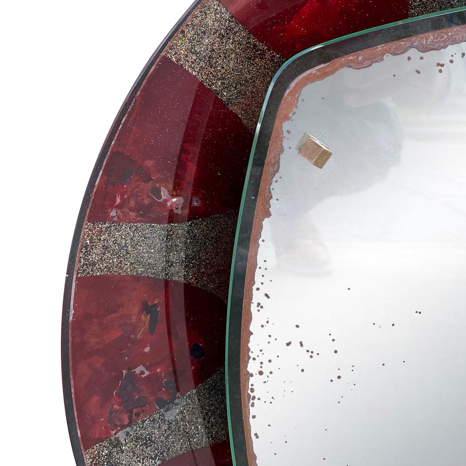Miroir mural italien rouge, rond, de style moderne du milieu du siècle, en verre polychrome fabriqué à la main, avec son verre miroir d'origine, produit par Santambrogio & De Berti, en bon état. Le miroir éclairé est composé de quatre prises de