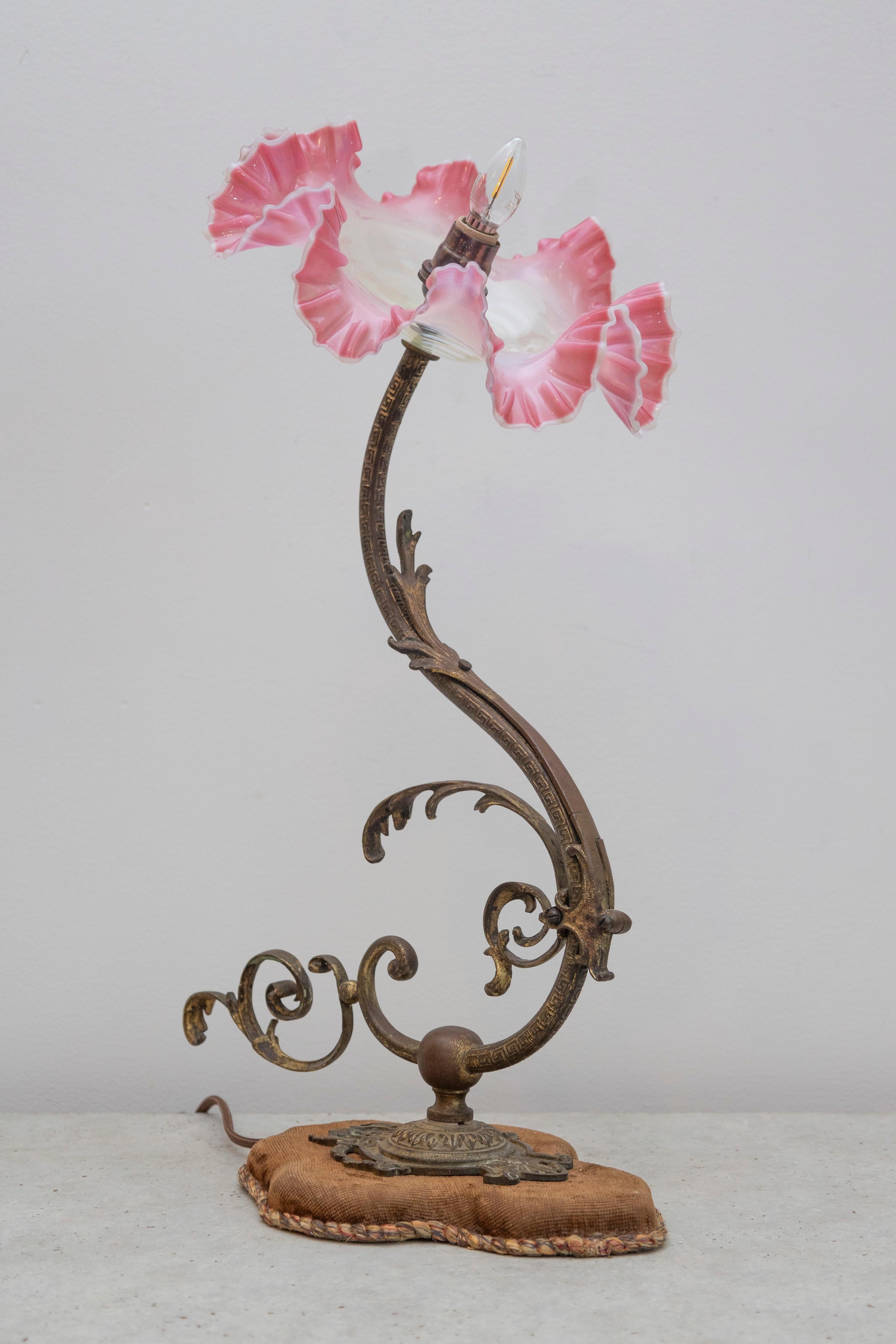 Cette lampe de table Art nouveau de la fin du XIXe siècle au début du XXe siècle, au design gracieux, capture les lignes organiques et fluides caractéristiques de ce mouvement. L'armature en bronze forgé s'incurve élégamment, ornée de délicats