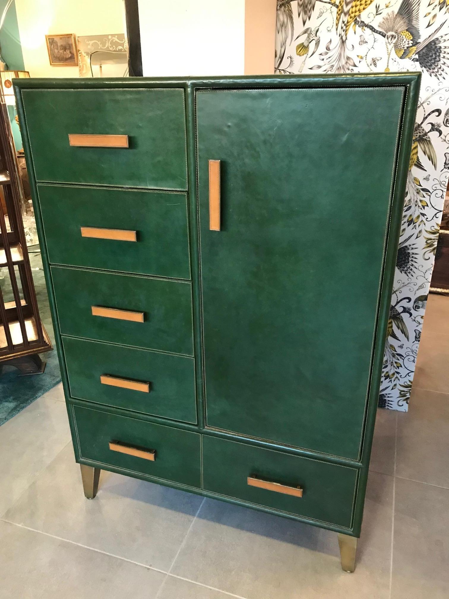 Beautiful 20th century Italian chest of drawers covered with a nice green leather and brown stitching. Brass and leather handles. Six drawers and one door that could be used as a wardrobe. The inside is covered with a stripe fabric. Gilded brass