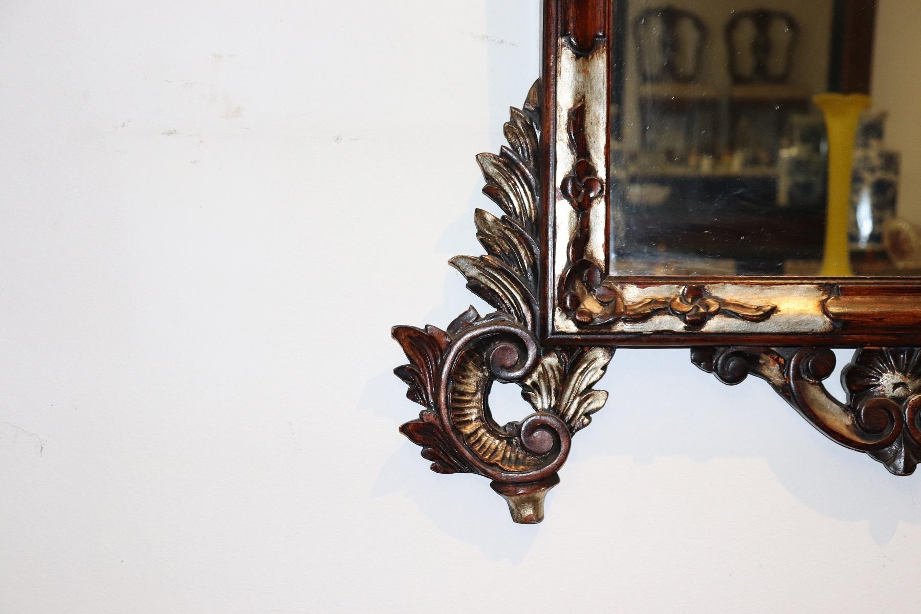 Luxuriöser Wandspiegel aus geschnitztem Holz im antiken Stil der 1950er Jahre mit raffinierter Dekoration in Silber und lackiertem Holz. Sehr reiche Arbeit im Stil Louis XV mit Locken und Wirbeln. Dieser Spiegel ist perfekt für ein raffiniertes und