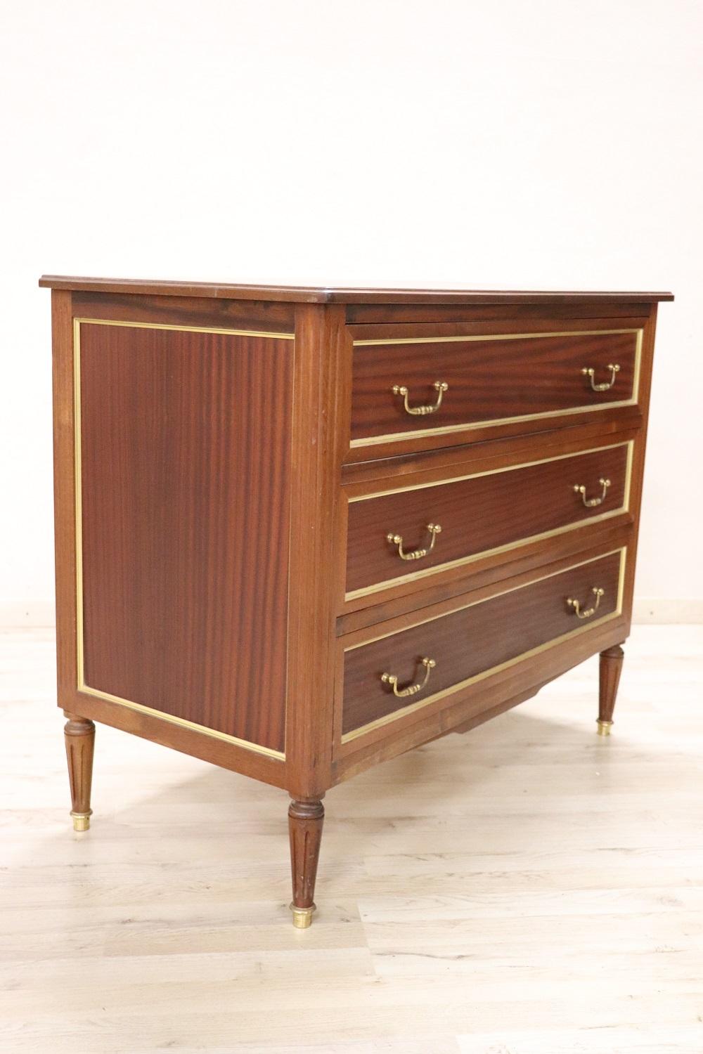 Rare and fine quality Italian Louis XVI style 1950s chest of drawer in elegant mahogany wood. On the front three comfortable drawers. Featuring elegant golden brass frames. Simple and elegant line. Beautiful slender legs. Due to its small size it is