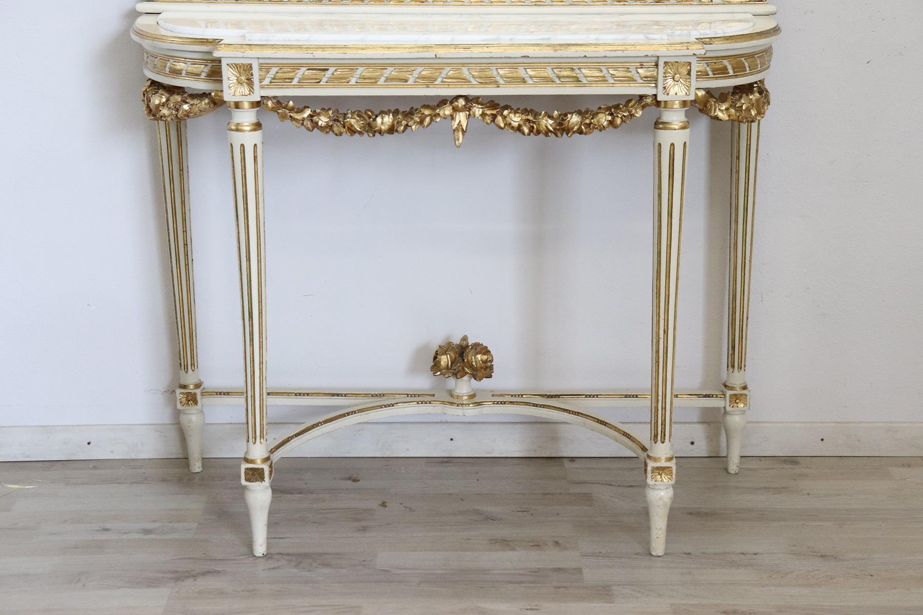 Italian Louis XVI style console table, 1950. Characterized by precious lacquered and gilded wood. The top is made a precious white Carrara marble. The wood is finely decorated with carving with wreaths and flowers . Many decorative elements of