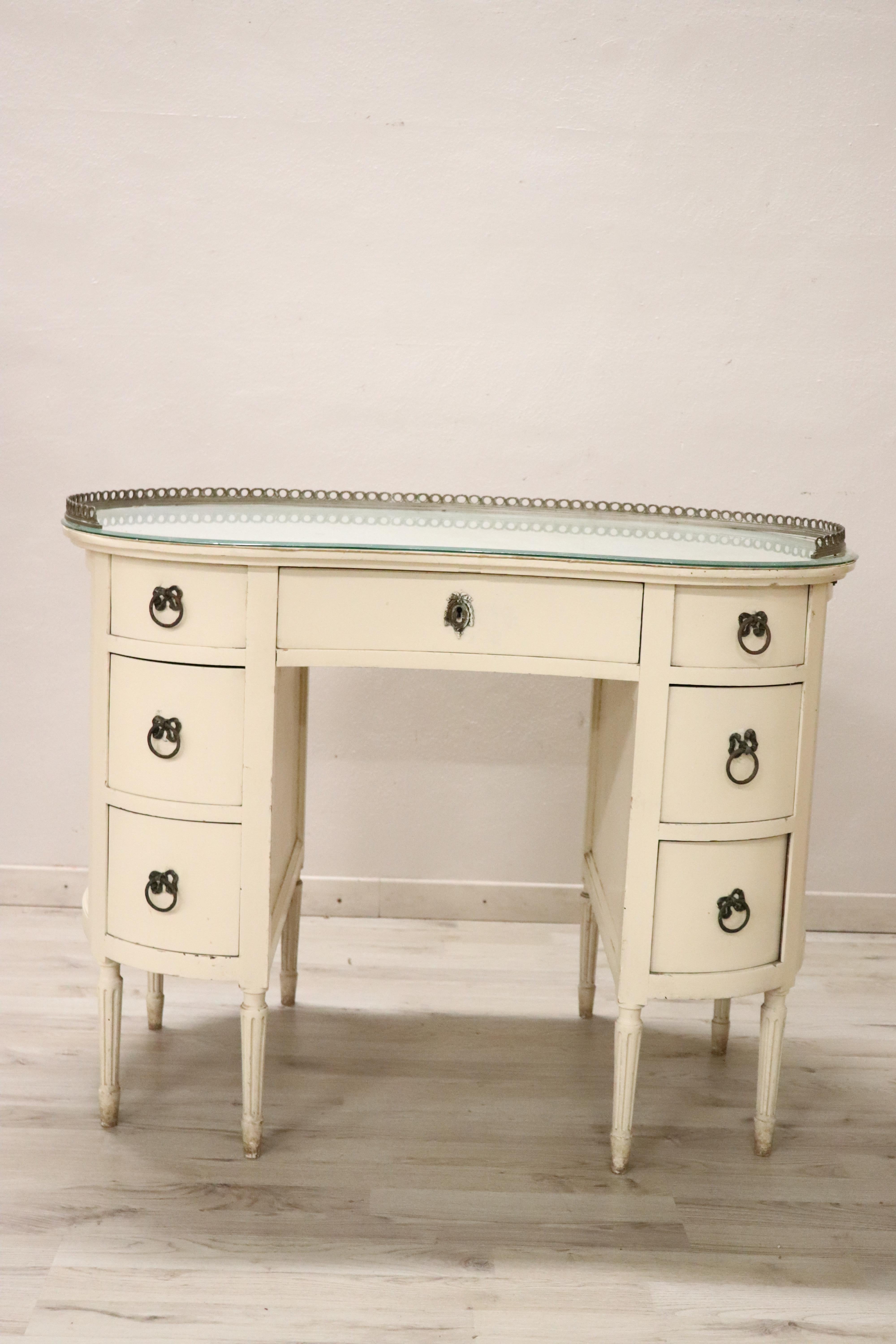 Rare and fine quality Italian Louis XVI style 1930s dressing table in white lacquered wood. The table has a particular bean shape, the top is covered with precious antique fabric and protective glass. Refined chiseled bronze decorations. Many useful