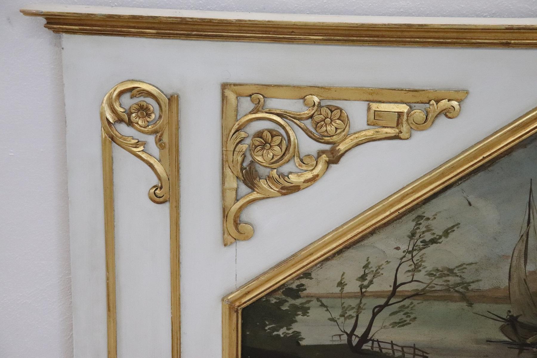 Beautiful elegant large fireplace mirror in perfect Louis XVI style, 1950s wood lacquered finely and richly carved with swirls of great refinement decorated in gold leaf. Above the mirror a beautiful oil painting on marine cardboard with ancient