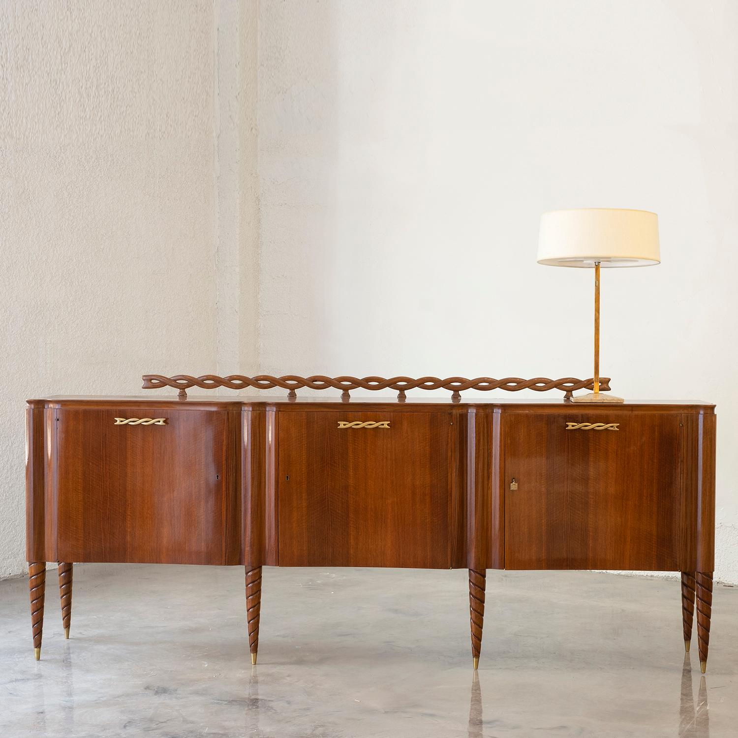 A light-brown, vintage Mid-Century Modern Italian credenza, sideboard made of hand crafted polished walnut with three doors and detailed brass handles, designed by Paolo Buffa and produced by Mario Quarti in good condition. The large cabinet is