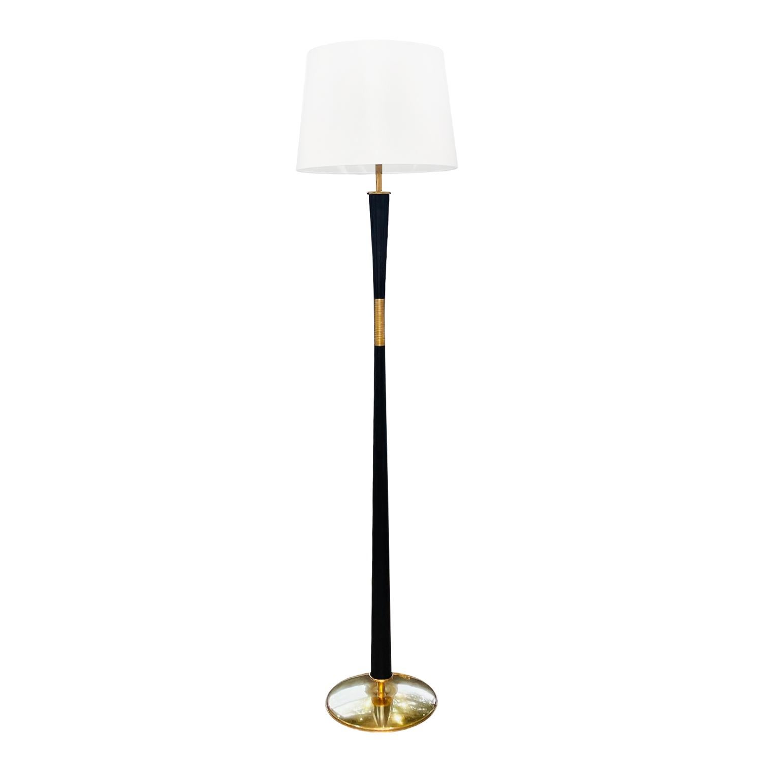 A vintage Mid-Century modern Italian floor lamp with a new white round shade, made of hand crafted iron in good condition. The tall light is enhanced by a polished ribbed brass ring, resting on a round base. The modern lighting is composed with its