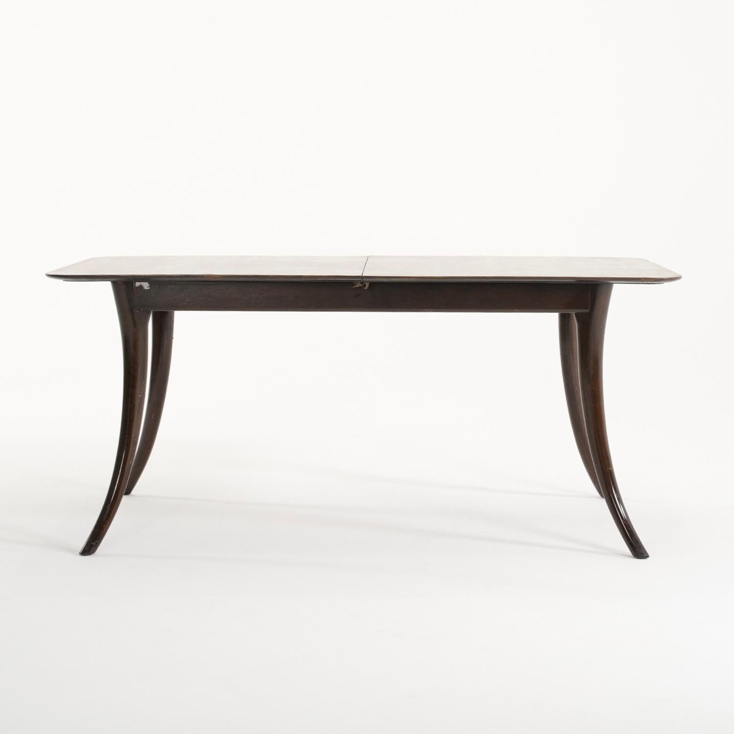 A vintage Mid-Century modern Italian dining room table made of hand crafted polished Walnut, in good condition. The rectangular conference table has a slim top, supported by a frame, standing on four long sculptural wooden legs. The table could also