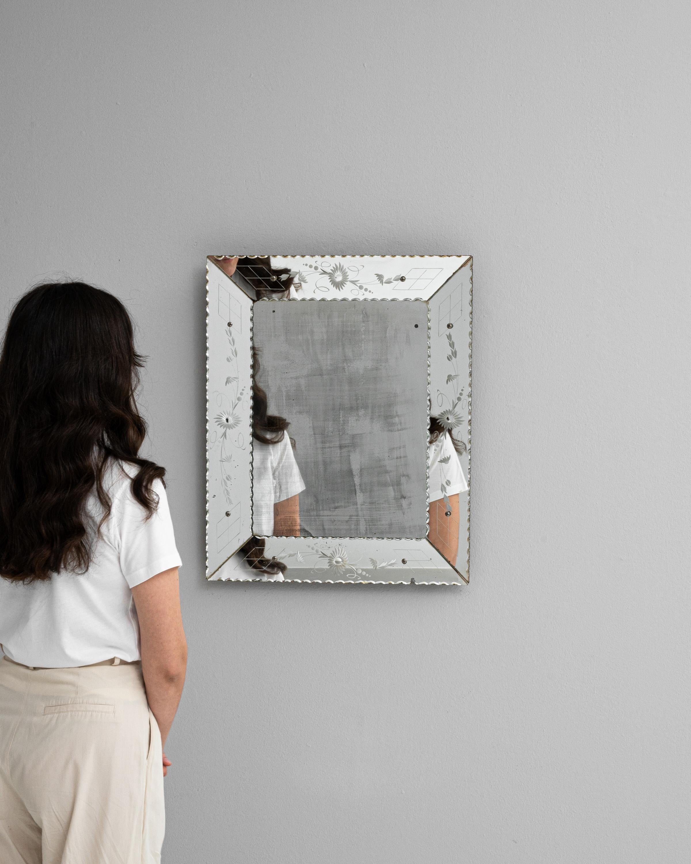 Experience the charm of Italian design with this exquisite 20th-century mirror, a testament to timeless elegance. Its reflective surface, bordered by a delicately etched frame adorned with subtle floral motifs, captures not just your reflection but