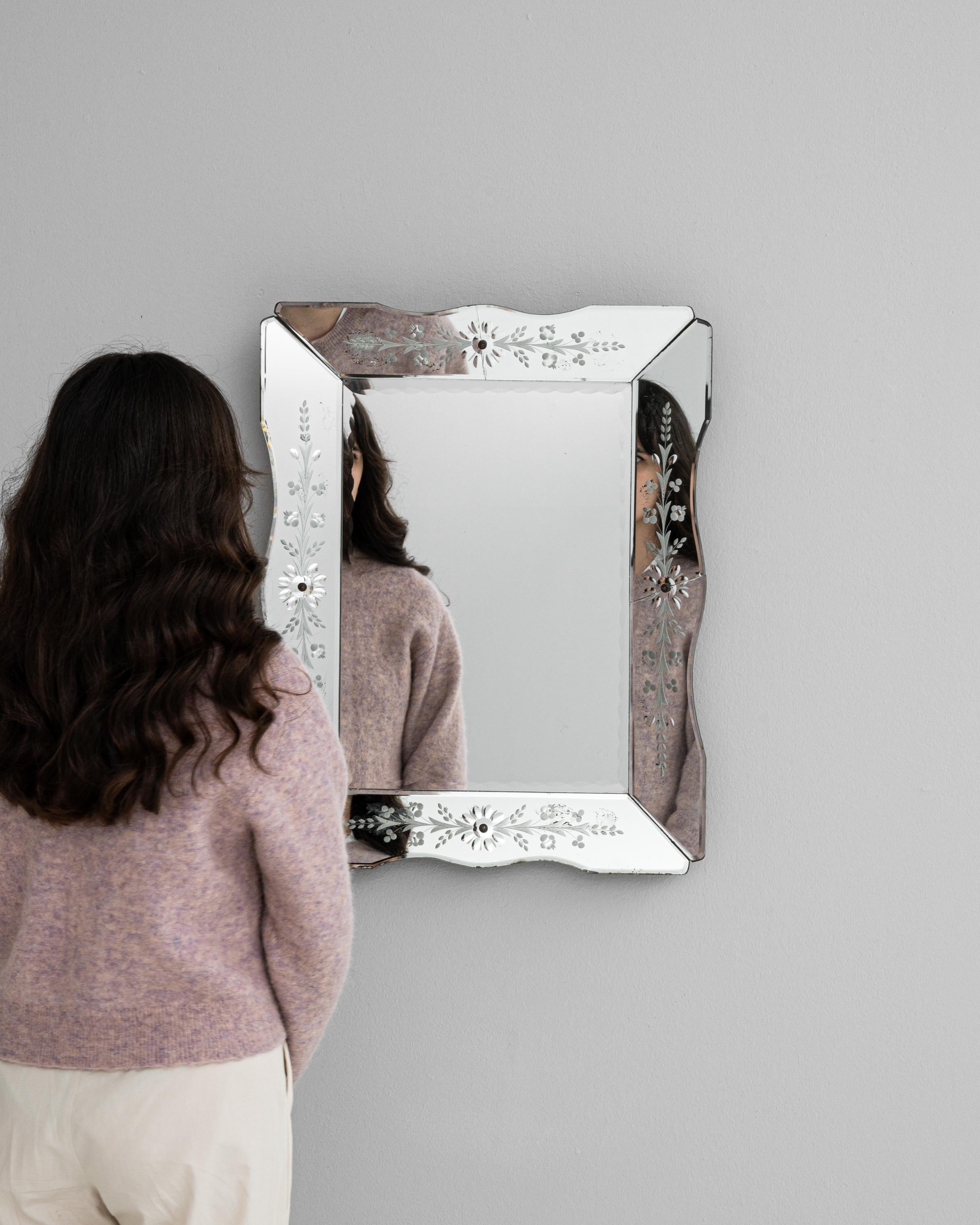 Experience the charm of Italian design with this exquisite 20th-century mirror, a testament to timeless elegance. Its reflective surface, bordered by a delicately etched frame adorned with subtle floral motifs, captures not just your reflection but