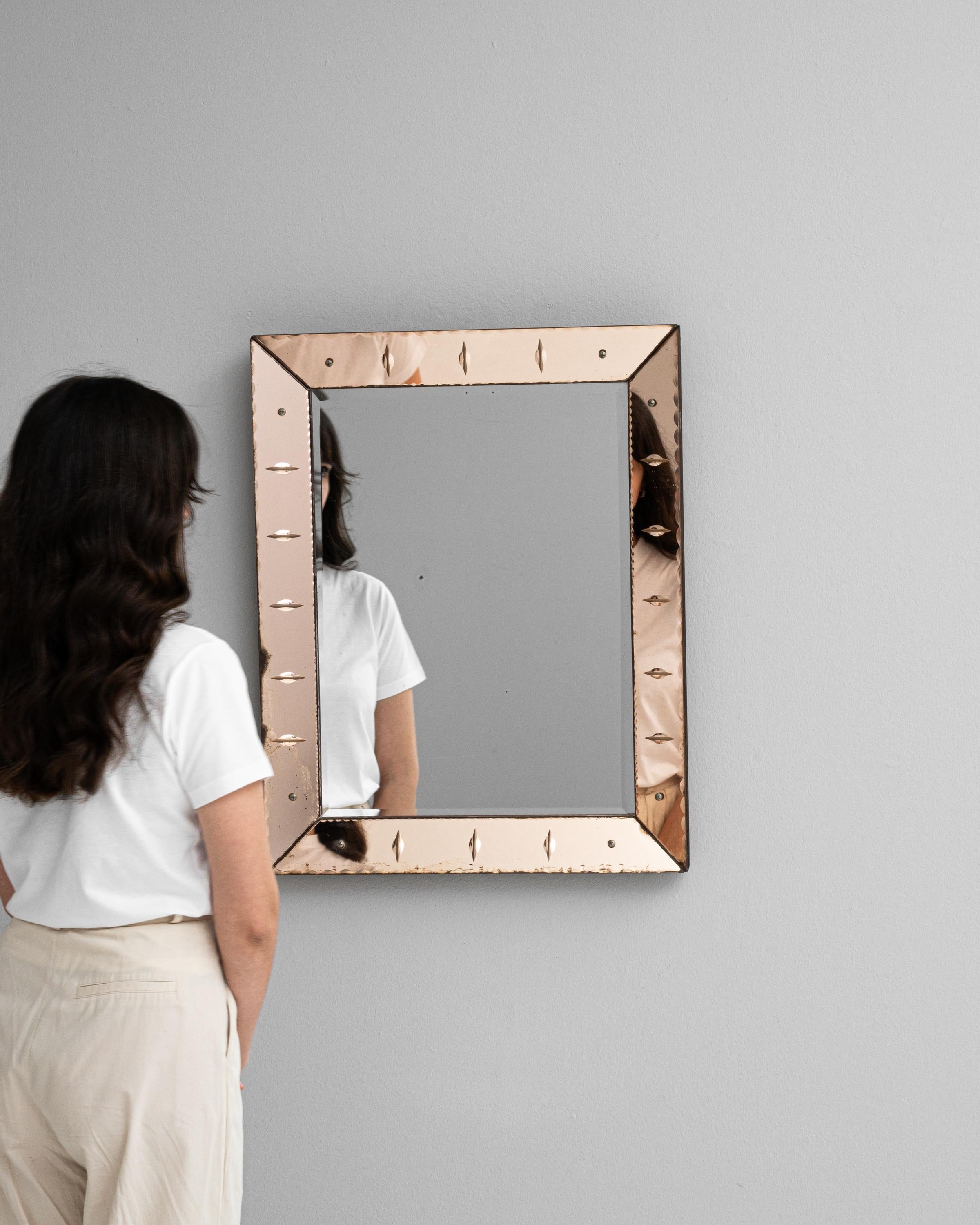 This 20th Century Italian Mirror is a charming reflection of minimalist artistry and mid-century design. The mirror, set within a sleek, square frame, is bordered by a delicate patina that suggests a gentle passage of time. The frame's understated