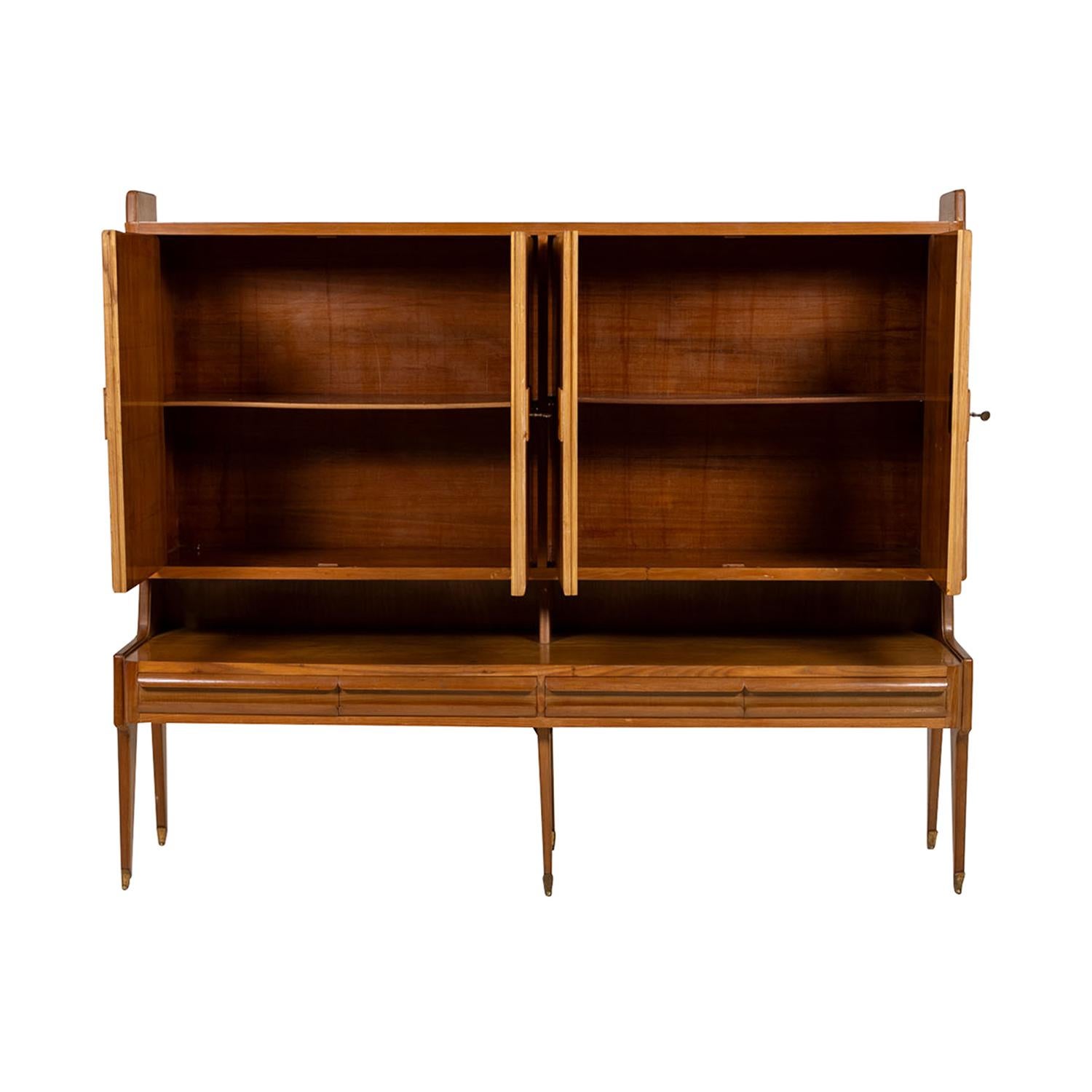 Une armoire italienne du 20e siècle, mince et moderne du milieu du siècle, faite de noyer et d'érable polis et travaillés à la main, probablement conçue par Osvaldo Borsani, en bon état. Le buffet détaillé est composé de quatre grandes portes,