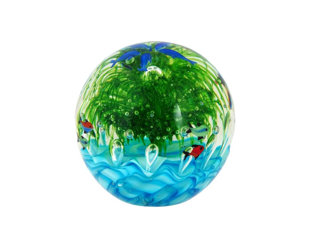 A large 20th century Italian hand blown glass paperweight by Murano. It is a round aquarium with a large a tropical reef with seaweed and exotic fish in the center, five dolphins are located in a circle on top. There are a large number of air
