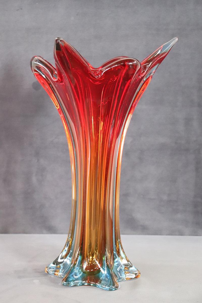 Refined Italian tall vase in Murano art glass, 1960s. This vase is characterized by a particular design shape. The vase is of high artistic quality made with the submerged glass technique. Thanks to this technique, the vase has a color that starts