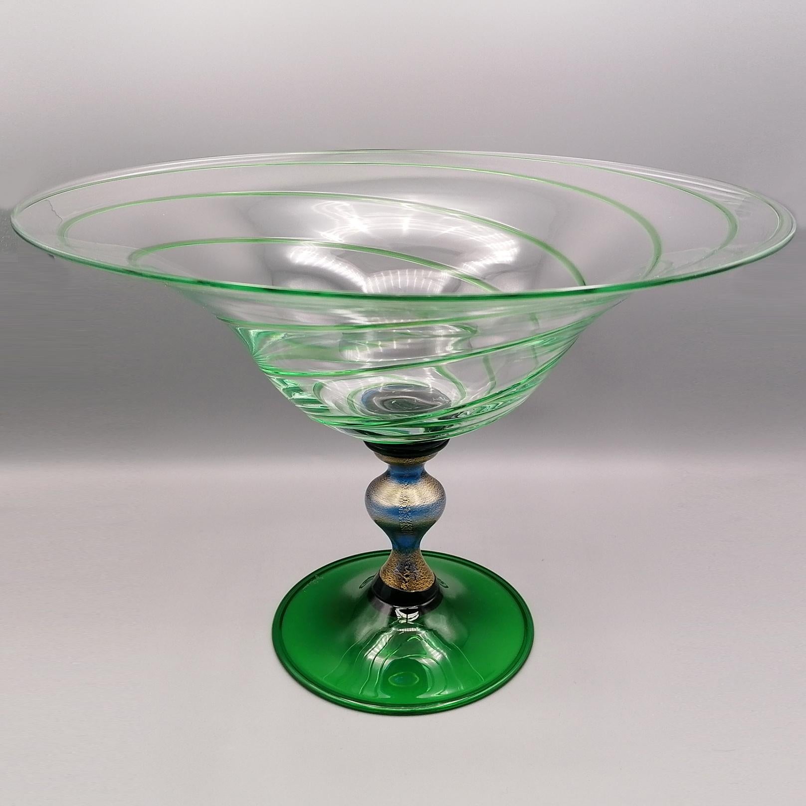 Glass centerpiece made in Murano - Venice - Italy by the Gabbiani artisan factory.
The base is green, while the stem is blue where flakes of pure gold have been inserted.
The cup is flared and made of clear glass, decorated with a green spiral