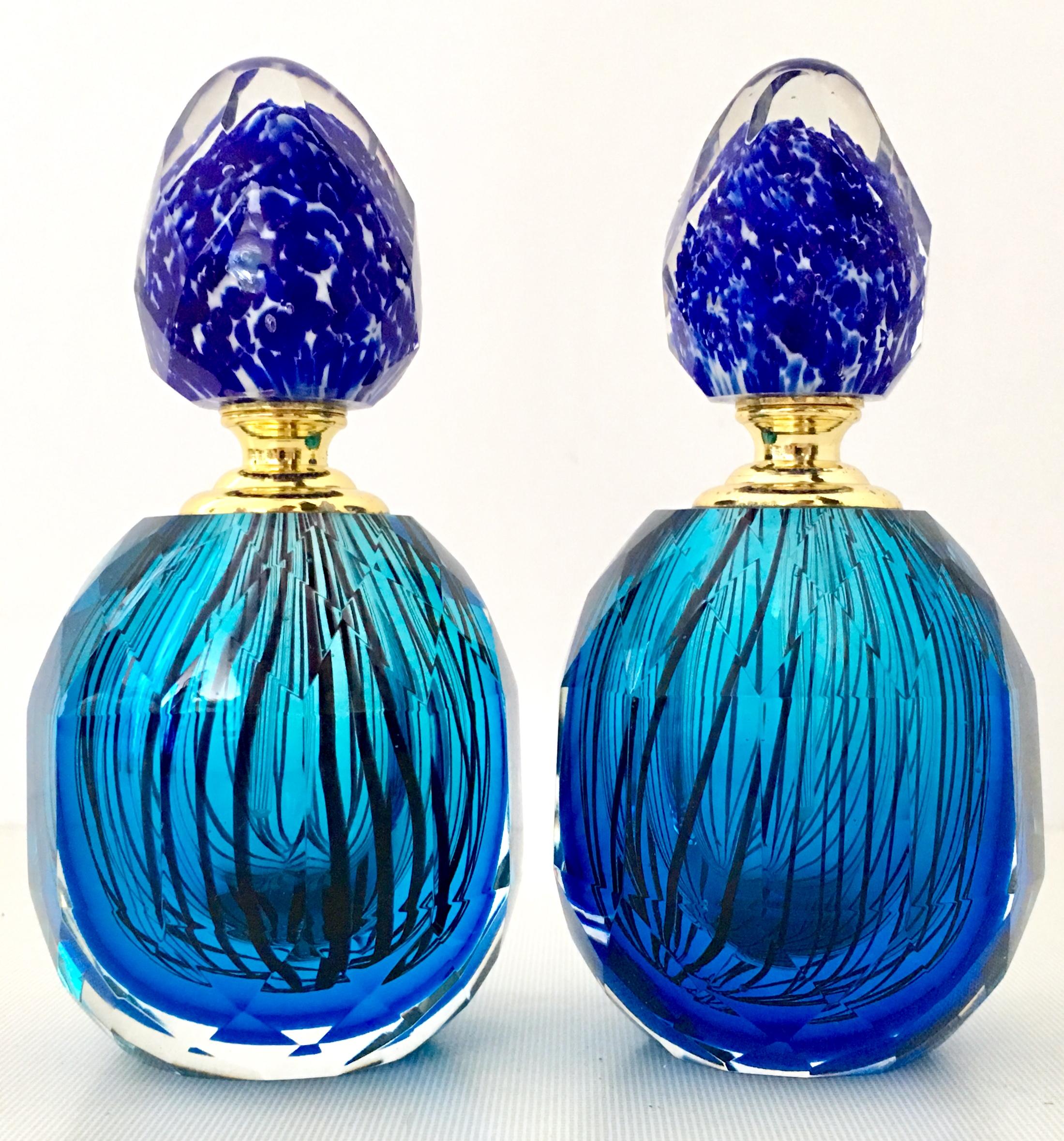 20th century Italian Murano glass style pair of perfume decanters. These brilliant cut and faceted blown glass decanters feature a vivid blue with cased black stripe body, and a speckled cased glass blue and white stopper. The gilt gold brass neck