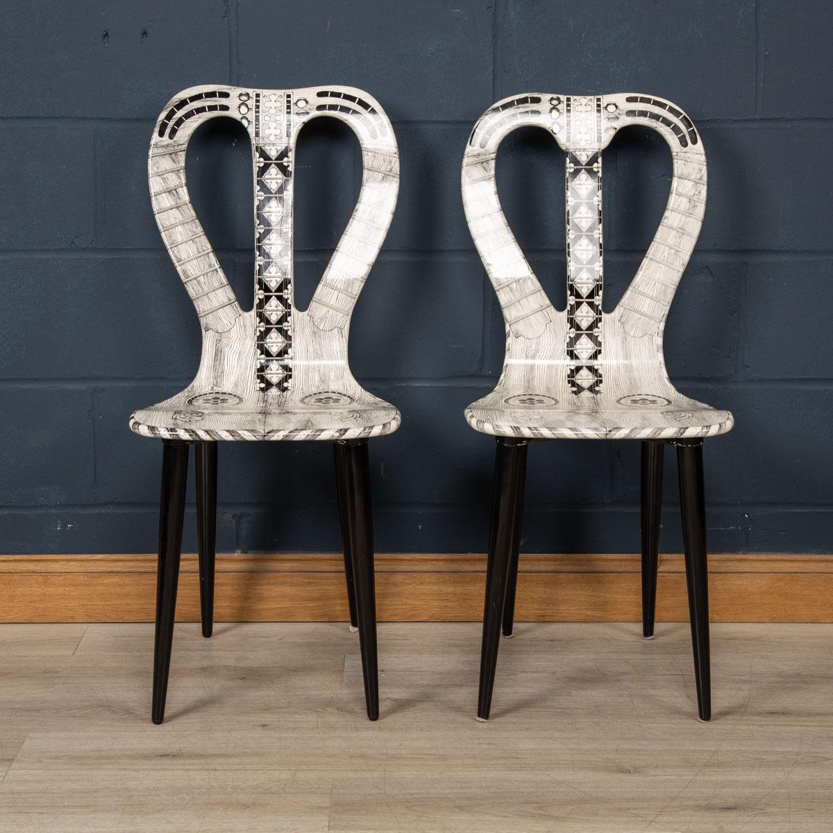 A very rare pair of chairs by Fornasetti Studios made in Italy towards the latter end of the 20th century. These chairs are handcrafted using the original artisan techniques. They are silk-screened by hand, hand painted and covered with a smooth