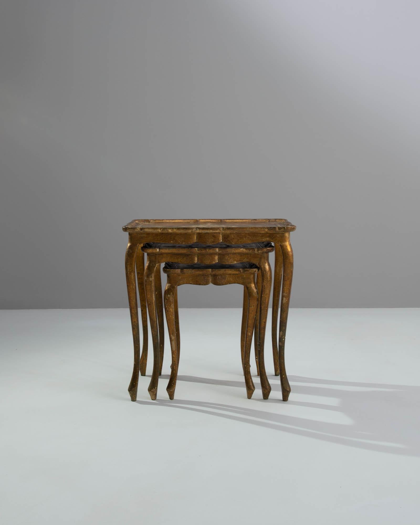 This trio of nesting tables evokes a bygone era of extravagance. Made in Italy in the 20th century, the design takes inspiration from the lavish furniture of Baroque palaces and stately villas. In particular, the embossed motif at center of the