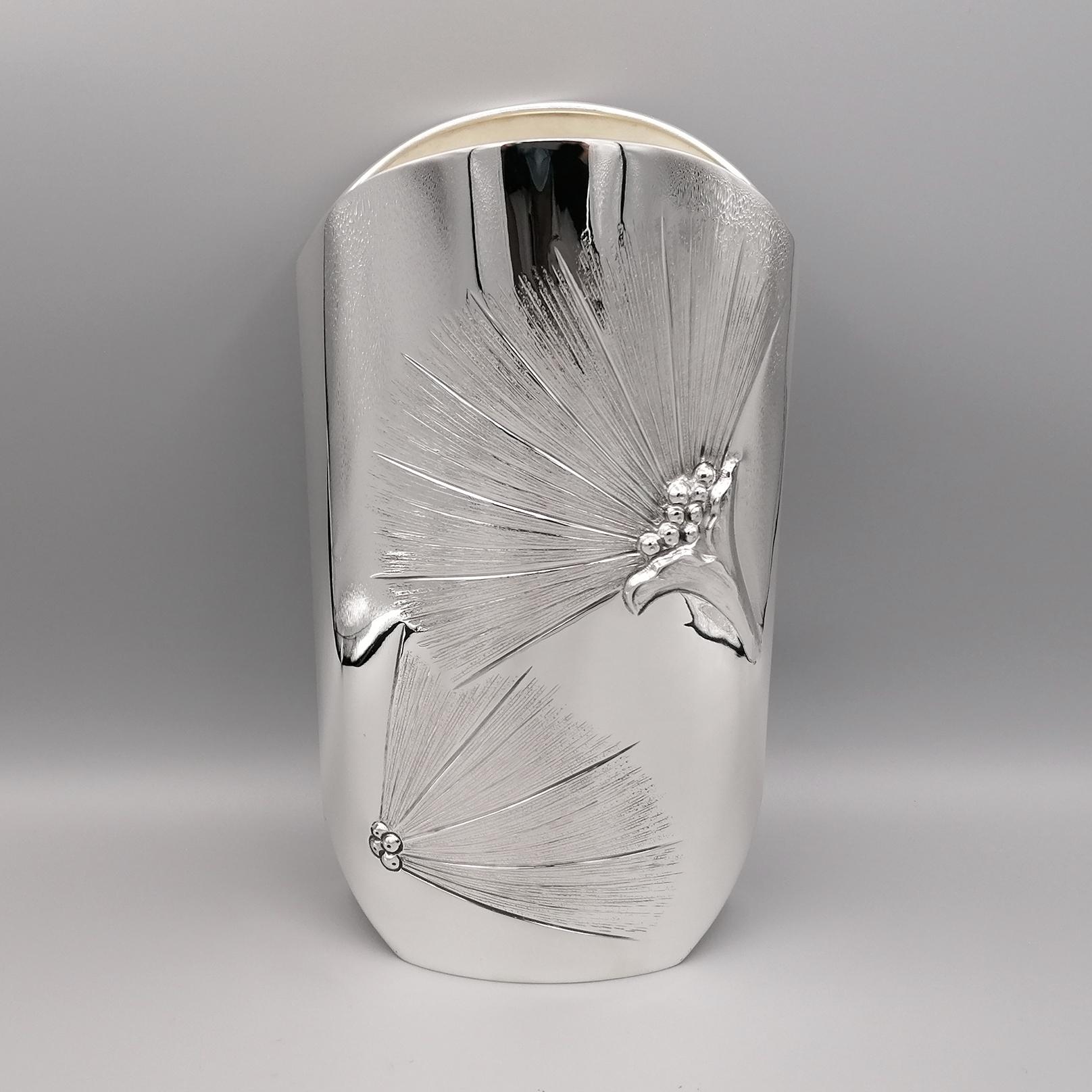 Vase aus 800 massivem Silber mit spitzer ovaler Form. 
Die Rückseite wurde völlig glatt gelassen, während die Vorderseite mit dem Muster der Sterlizia-Blüten geprägt und gemeißelt wurde. Vollständig handgefertigt von dem Silberschmiedemeister