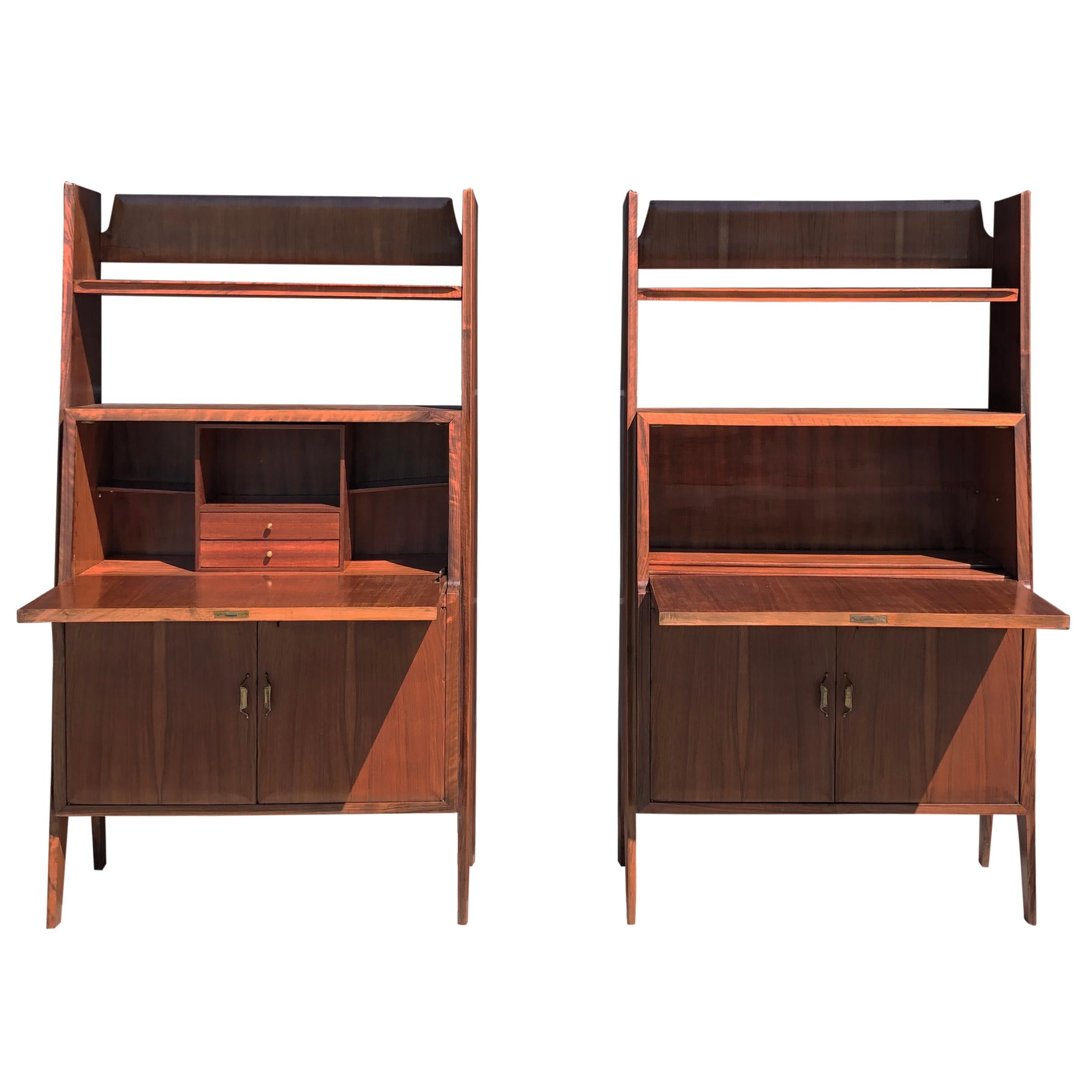 A dark-brown, vintage Mid-Century Modern Italian pair of cabinet writing desks (his and hers) with a two door bases and shelving tops, designed by Silvio Cavatorta. The front writing surfaces shows the beautiful inlays of typical classic motives in