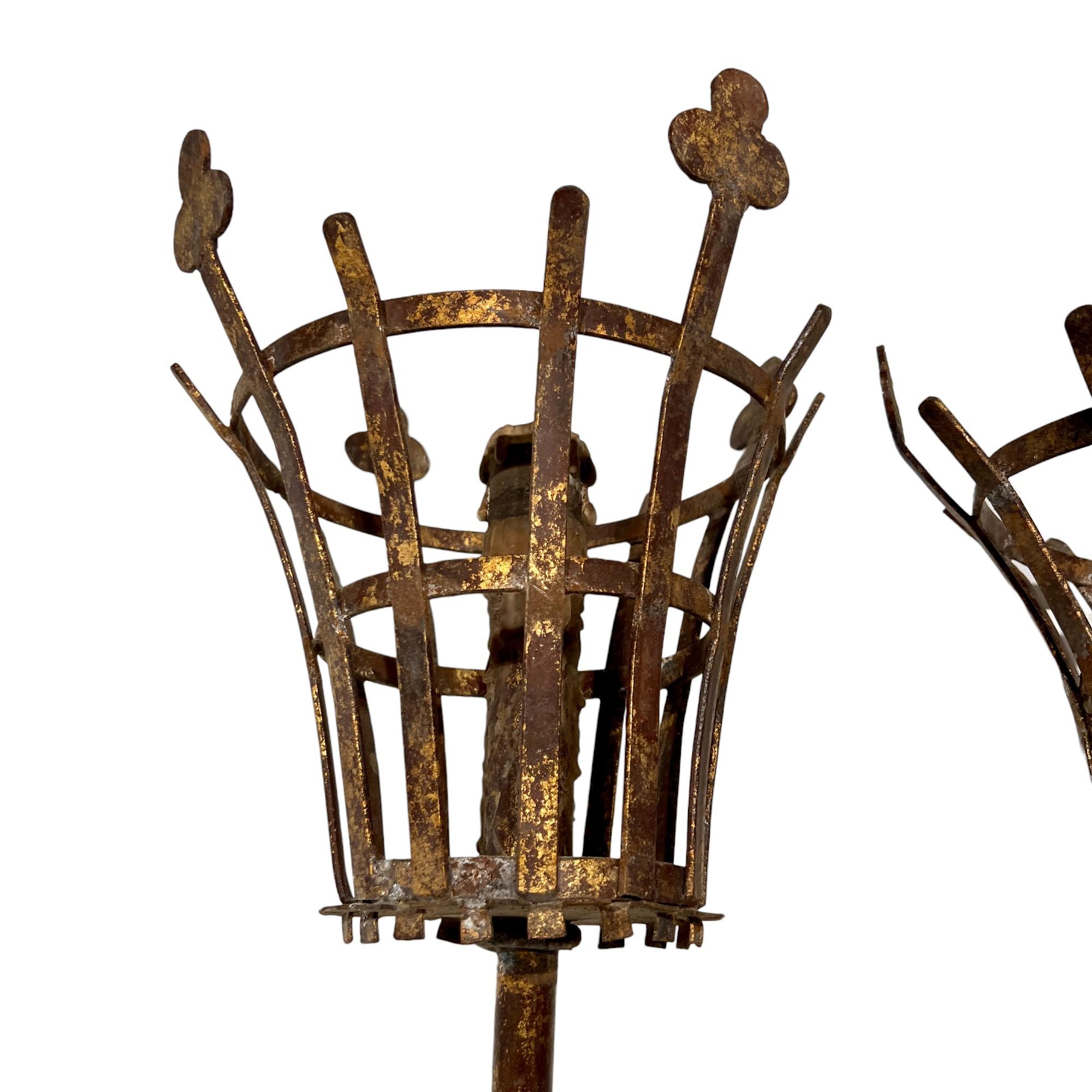 Questa coppia di grandi appliques in ferro del XX secolo presenta tipicamente motivi foliati o acanti e accenti dorati o policromi. Hanno una patina d'altri tempi, che ricorda l'artigianato forgiato a mano del XVI secolo, ma con un'esecuzione