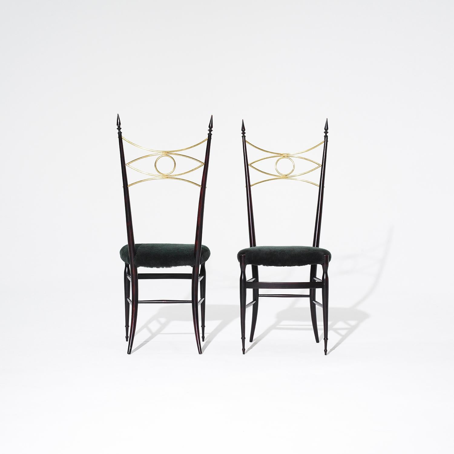 A vintage Mid-Century modern Italian pair of high sculptural side chairs made of hand crafted ebonized Rosewood, designed most likely by Paolo Buffa in good condition. The detailed dining chairs are particularized with an eye-shaped brass bracing