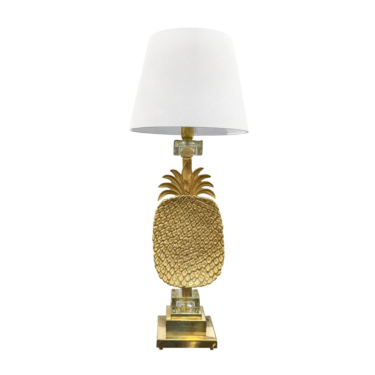 A vintage Mid-Century modern pair of Italian pineapple table lamps with a new beige round shade, made of hand crafted polished brass in good condition. The large lights are enhanced by two clear Murano glass blocks, featuring a single light socket.