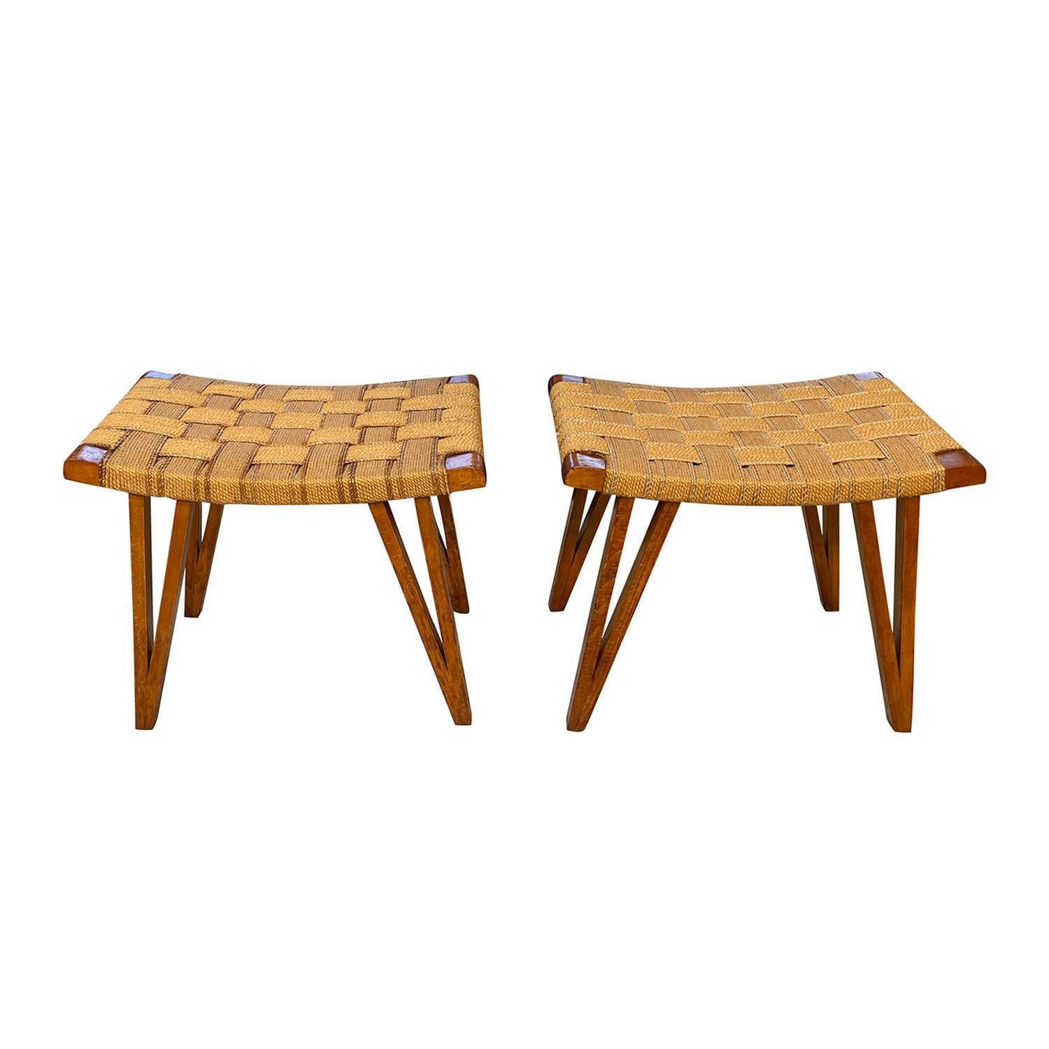 A vintage Mid-Century modern Italian pair of stools made of hand crafted waxed Oakwood designed by Augusto Romano, in good condition. The similar seat covers of the ottomans are made of woven hemp, standing on four arched wooden legs. Wear