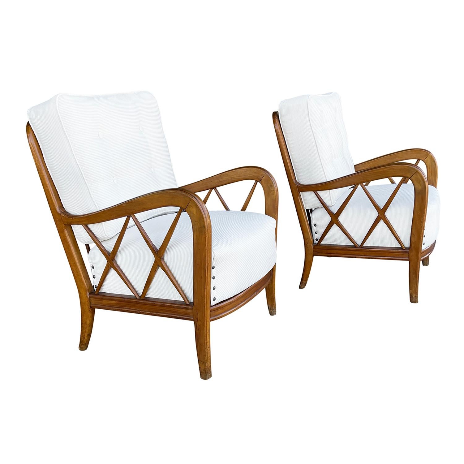 A vintage Mid-Century Modern Italian pair of armchairs made of hand carved Walnut. The backrest of the lounge chairs are spindled with X-form slats arms with a button-tufted back cushion and metal nailheads, standing on four wooden tapered legs.