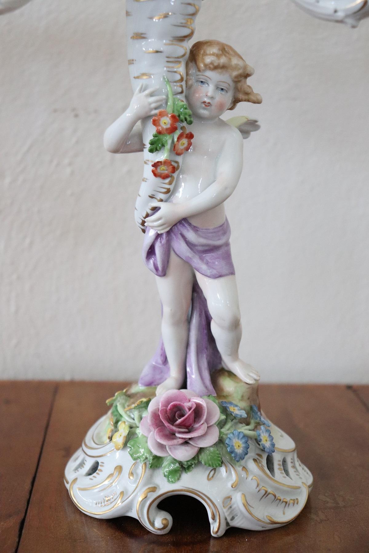 Beautiful and refined Italian pair of candlestick. Candlesticks are a masterpiece of the manufacture of Cpodimonte made entirely of ceramic hand painted. Many decorative elements make this candlesticks unique, many colorful flowers and cherubs