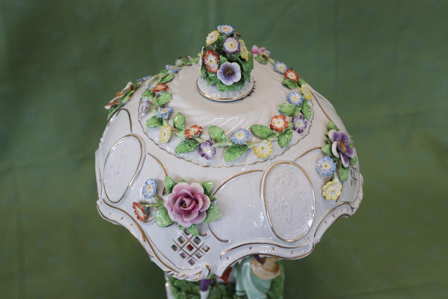 Beautiful sculptural table lamp in refined italian Capodimonte porcelain. The lampshade is a masterpiece with multicolored roses and beautiful lithophane (transparent porcelain) scenes that can be seen when the lamp is lit. Equipped with two bulbs.