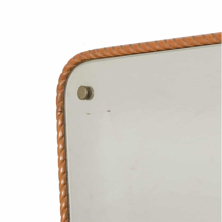 A light-brown, vintage Mid-Century Modern Italian wall mirror with its original mirror glass, enhanced by brass nailheads, designed by Paolo Buffa in good condition. The backside of the rectangular mirror is made of handcrafted mahogany. One brass
