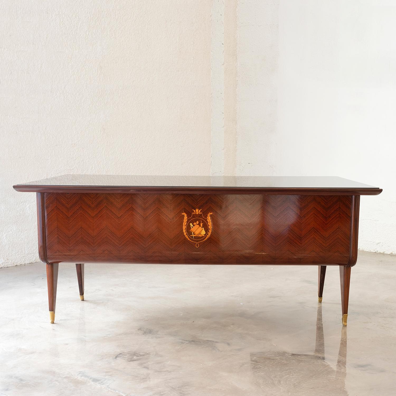A dark-brown, vintage Mid-Century Modern Italian half-round writing desk with a clear glass top, made of hand crafted polished Rosewood, designed most likely by Osvaldo Borsani and Paolo Buffa in good condition. The slightly curved table is composed