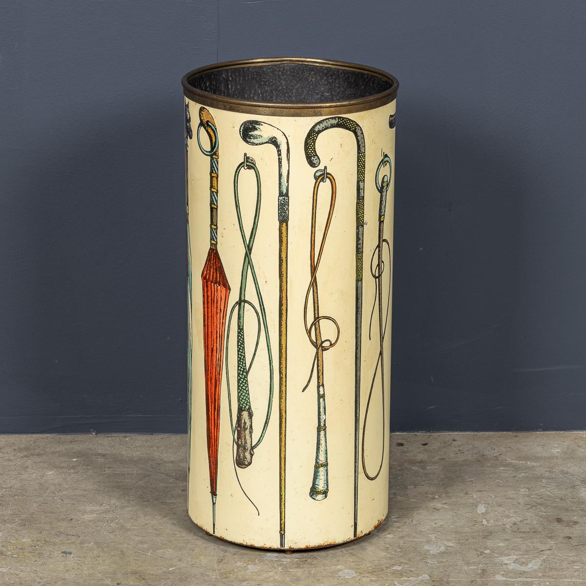 Ce porte-bâtons en métal italien du XXe siècle, conçu par Piero Fornasetti, présente un design unique avec des parapluies et des bâtons encerclant le couvercle extérieur. L'intérieur est peint en noir et le dessus est rehaussé d'un rebord en laiton.