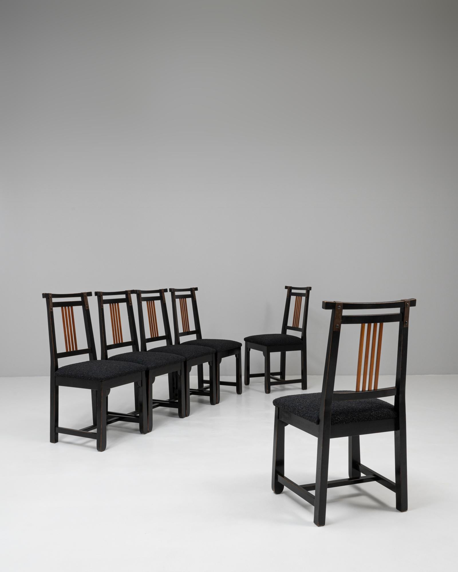 Questo set italiano del XX secolo di sei sedie da pranzo imbottite e patinate in nero presenta un'estetica elegante e modernista con sottili tocchi decorativi. Ogni sedia presenta una robusta struttura in legno rifinita con una patina nera profonda,