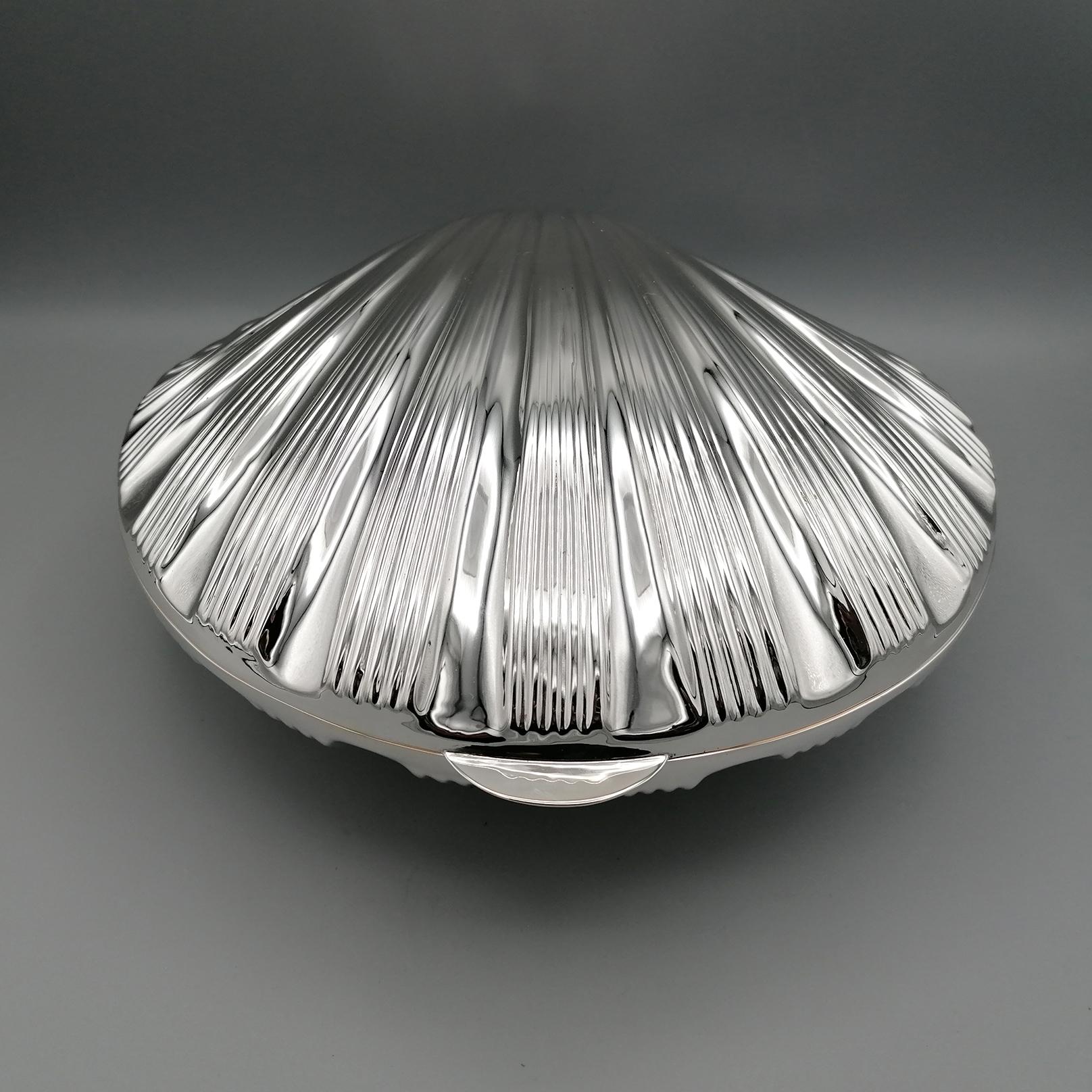 Shell-shaped box in solid 800 silver  completely handmade. 
The lower part and the lid have been shaped and chiseled by faithfully copying the veins and structure of the Chlamys shell and then joined by a hinge.
Under the box, three seahorses have