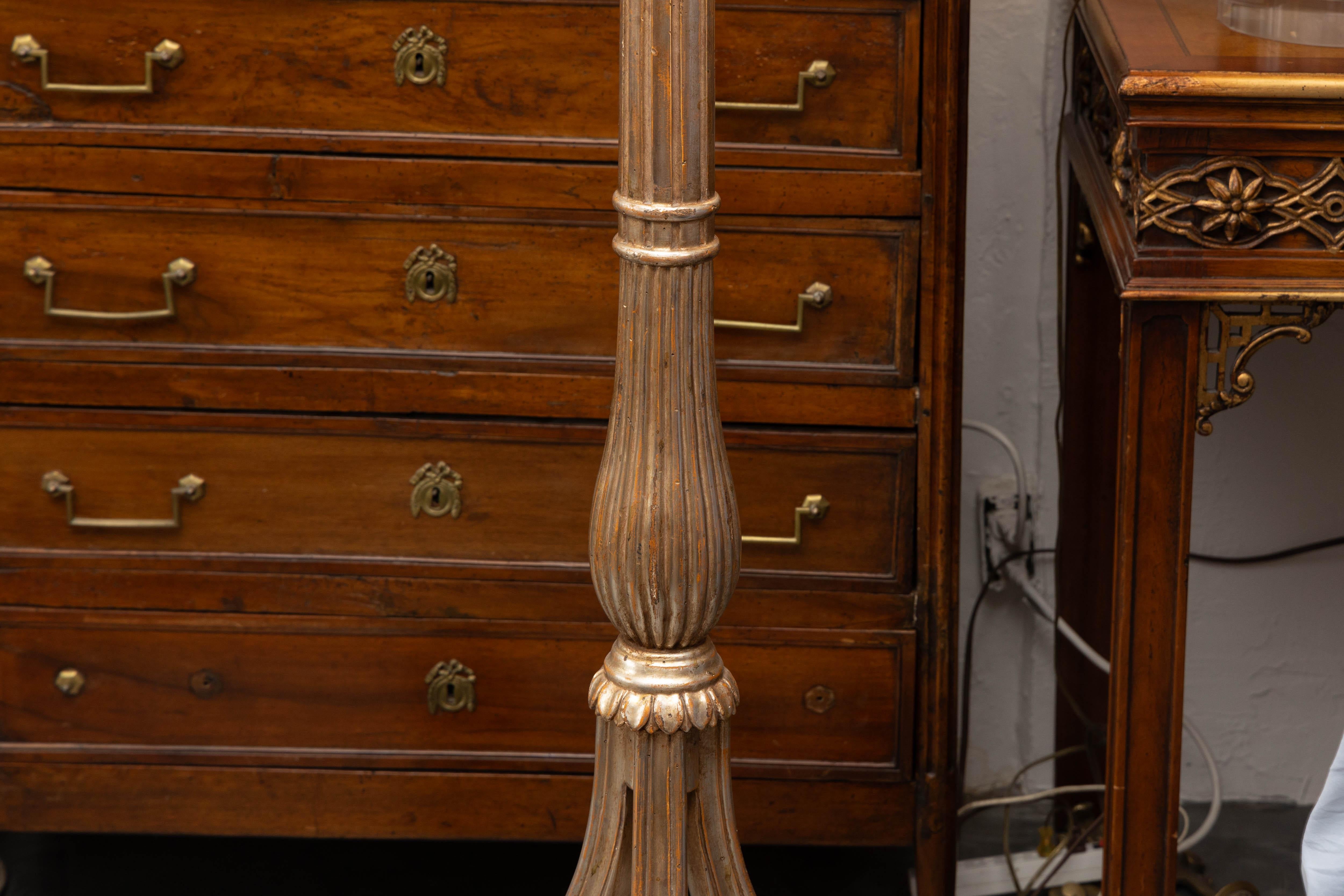 This is an elegant Italian hand carved silver-gilt floor lamp with a circular fluted stem, situated on a scrolling tripartite base attached to a solid plinth.