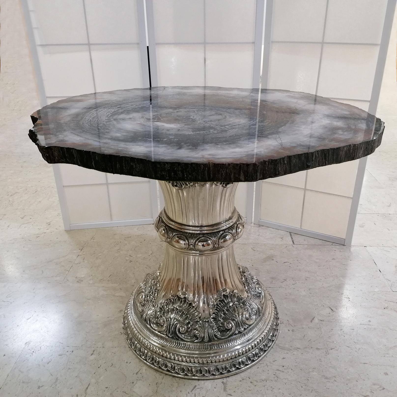 The table base is in solid silver 925°°/°°° gr. 6.000 in Italian Baroque style bearing the typical embossed and chiseled shells, with three layers of leaves and ovules. The central section, with embossed shiny round elements of two different