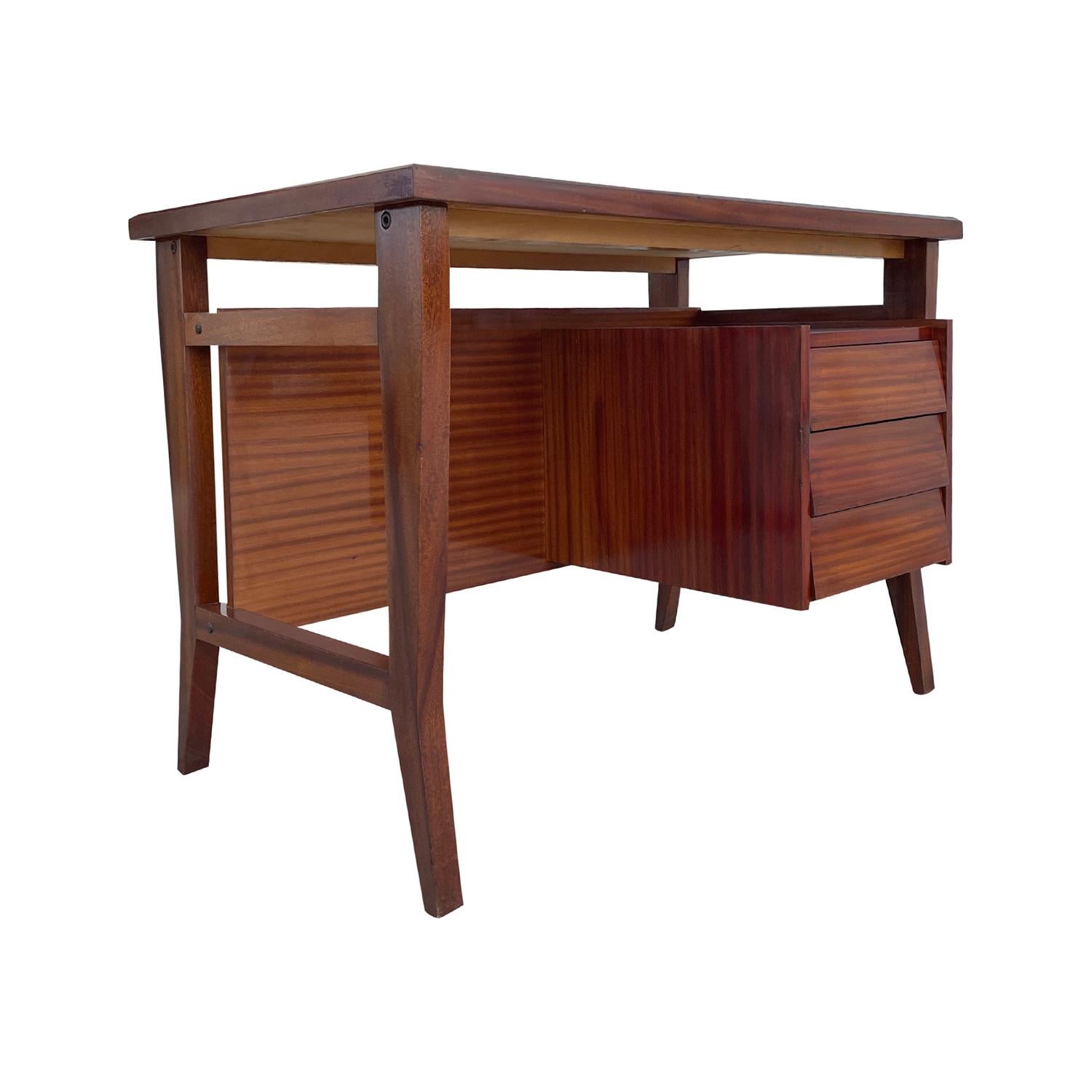 A vintage Mid-Century modern Italian writing table made of hand carved Mahogany, designed by Gio Ponti and produced by Schirolli Mantova in good condition. This rectangular desk has a white-grey formica top and three drawers, each featuring a