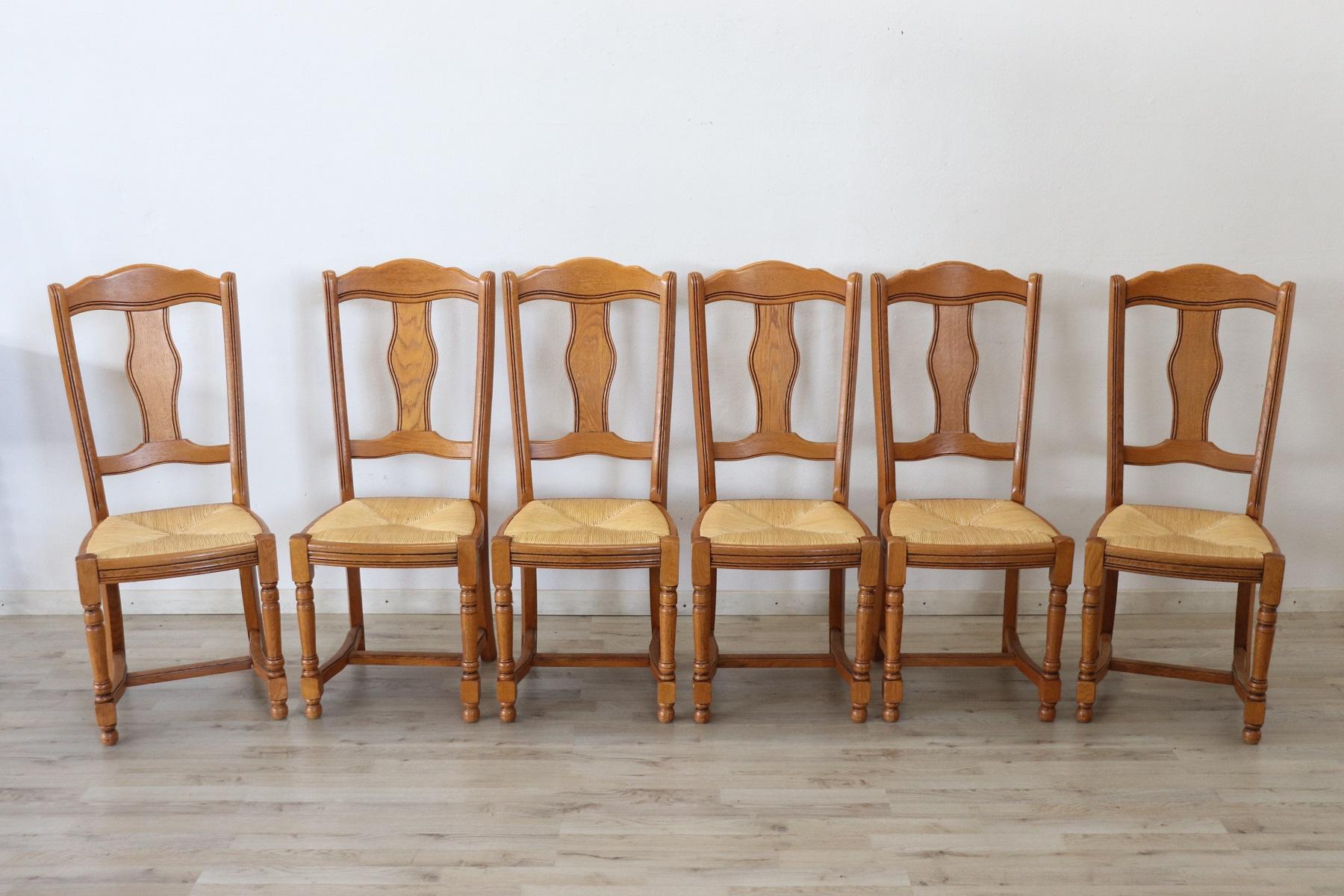 20th century Italian classical style dining room set of six chairs in solid oakwood. The chairs are very elegant and linear with turned legs. The seat is wide and comfortable in rustic straw. The chairs are in perfect condition ready to be used in