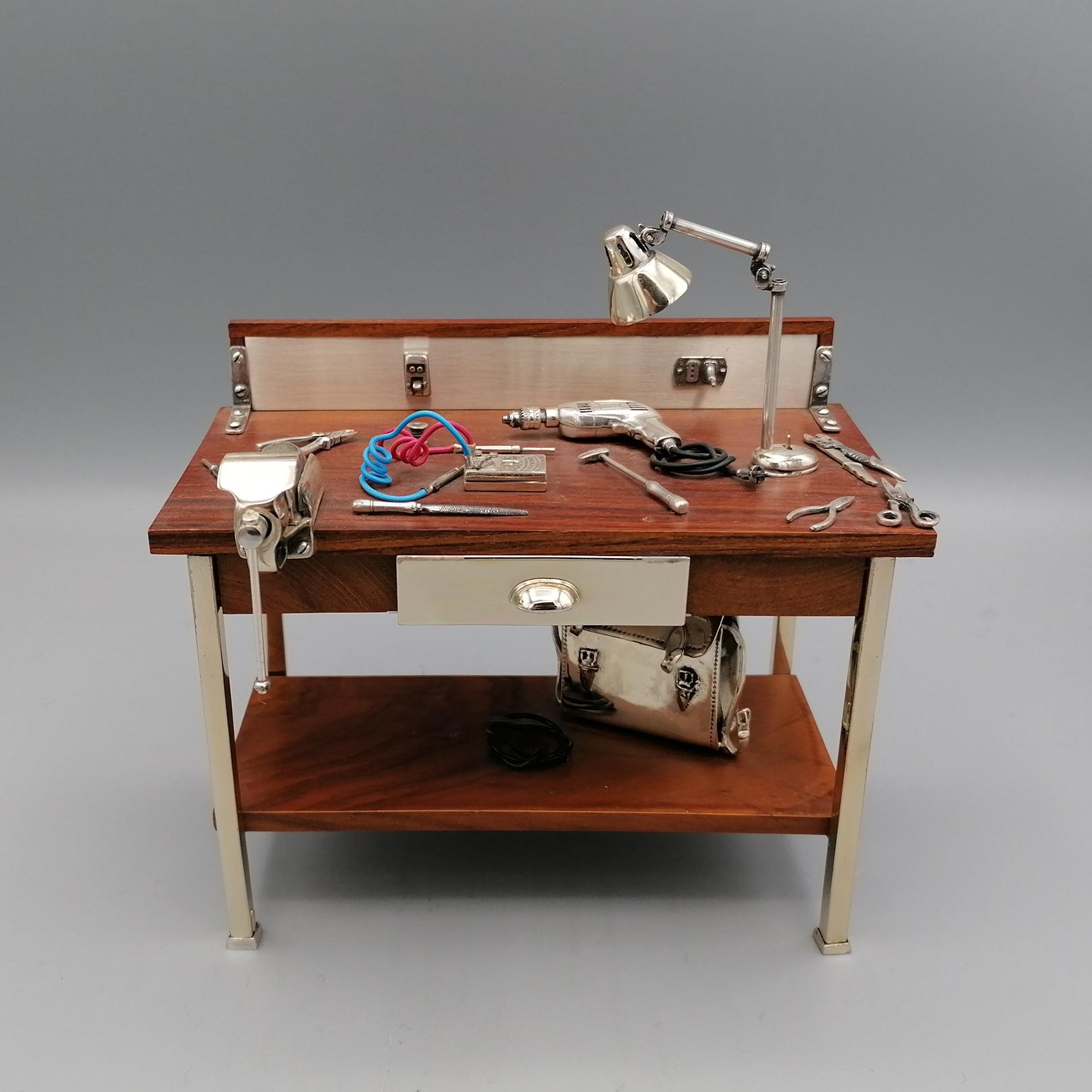 Electrician's workbench in wood and silver.
This miniature that reproduces the electrician's workbench was made in Arezzo - Tuscany - Italy by the master silversmith Sacchetti, specialized in the creation of silver miniatures.
The workbench is in