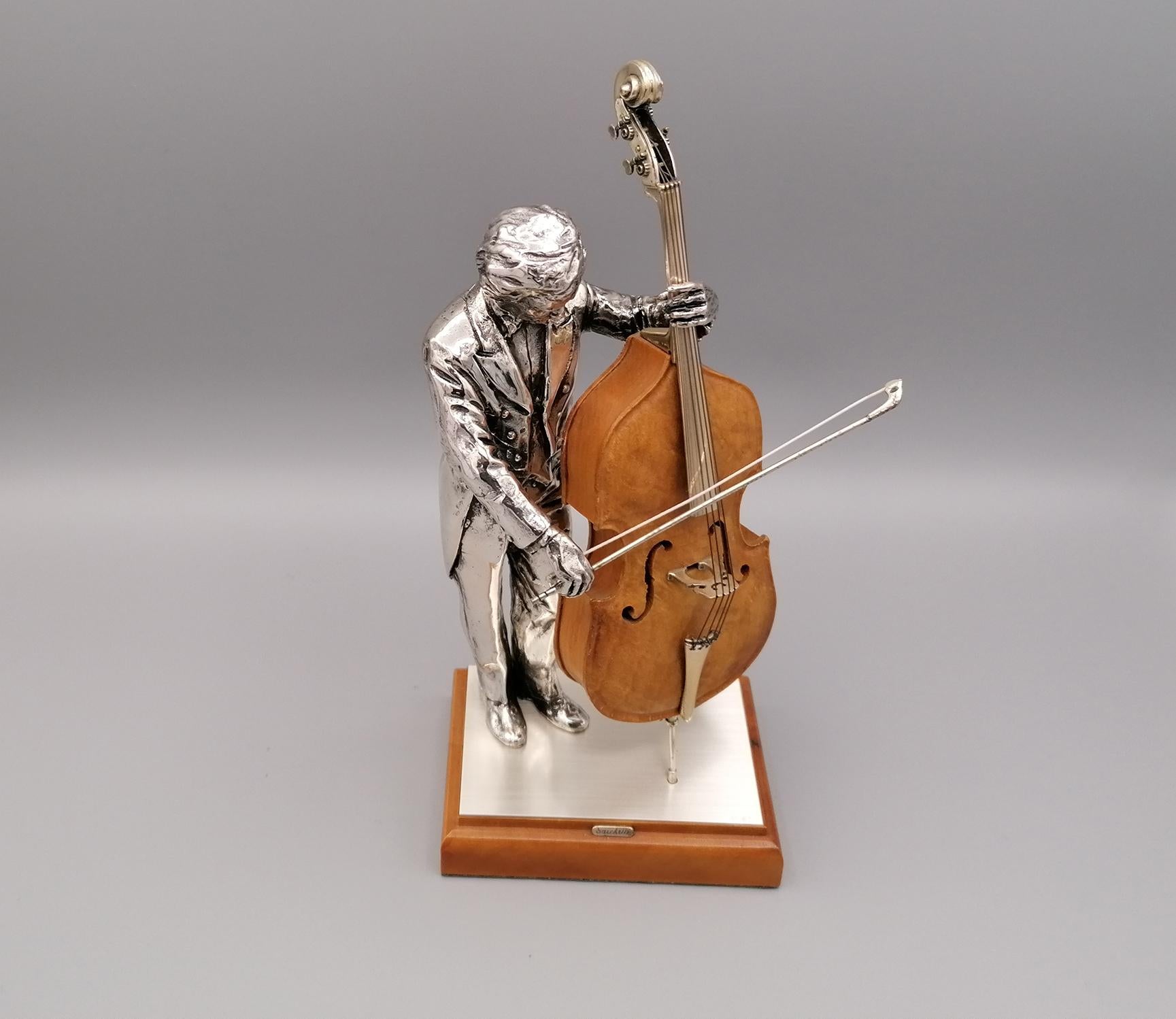 Double bass player in 800 solid silver. The double bass is in briar with silver details. 
The double bass bow is in silver.
The player and the double bass are positioned on a wooden base covered with a silver sheet at the top.
Italian silverware,