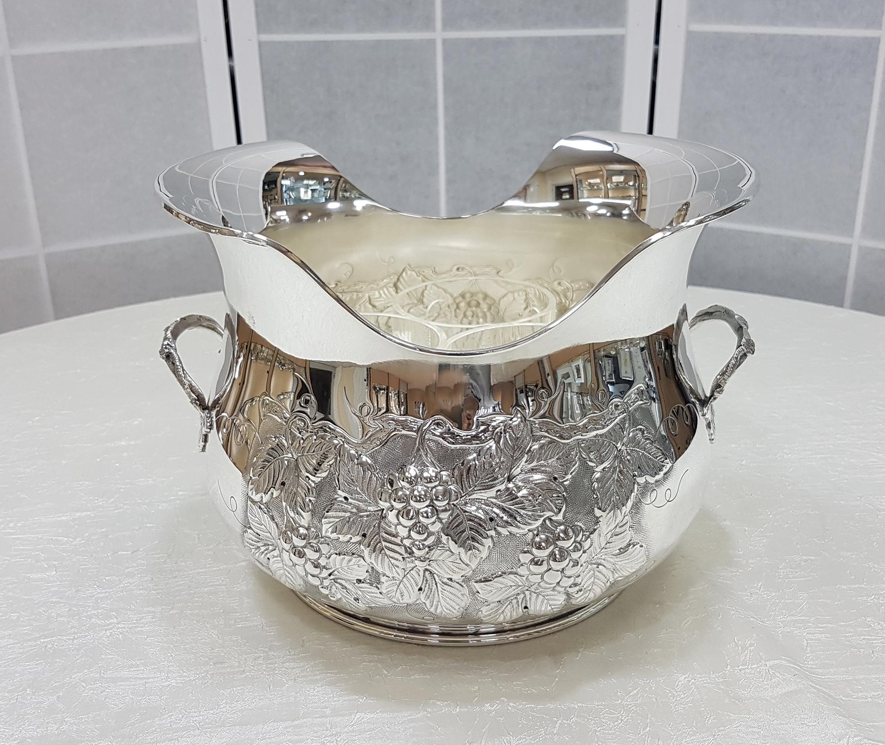 Gorgeous champagne bucket completely handmade, embossed, chiseled by hand with a design of bunches of grapes and leaves. The shape is round and with a shaped upper edge. The champagne bucket is completed by two solid handles, also in solid silver,